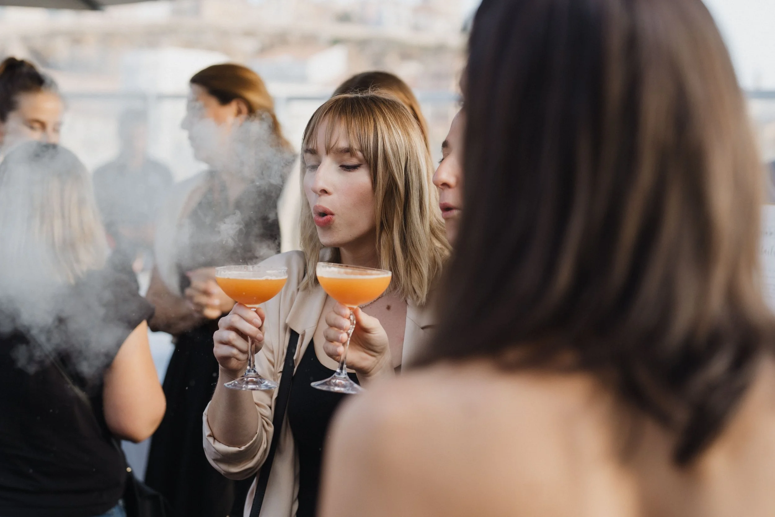 Groupe de femmes à une fête dégustant des cocktails, avec un décor intérieur en arrière-plan.