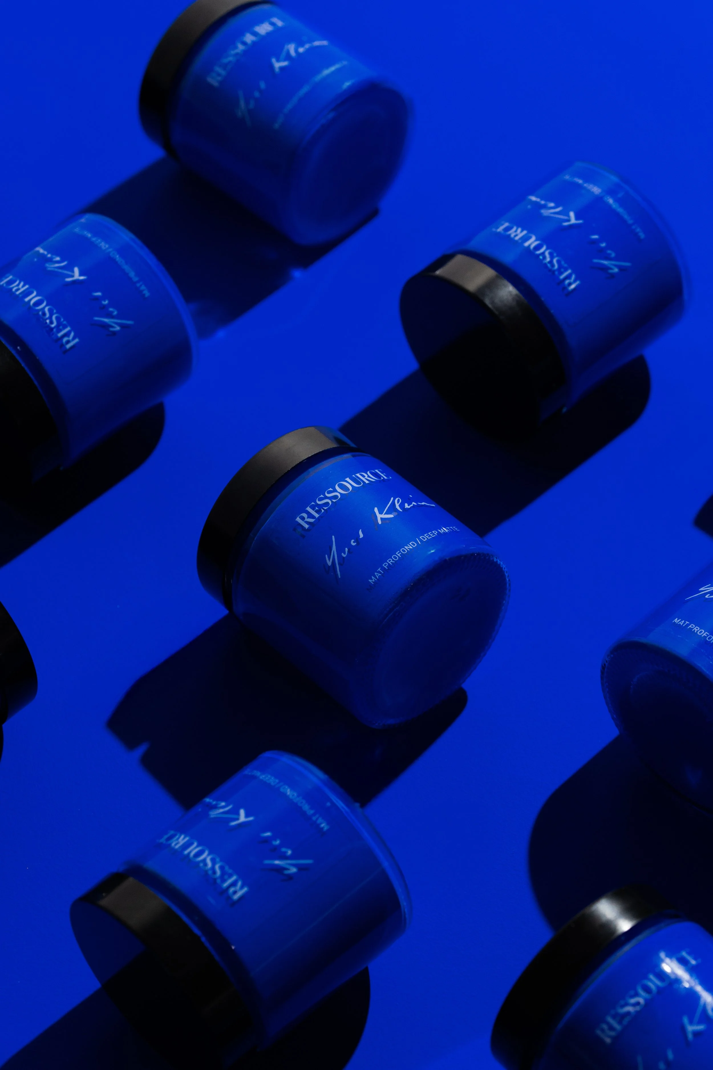 Contenants bleus de crème ou de produit de soin, disposés sur une surface bleue, avec des ombres nettes