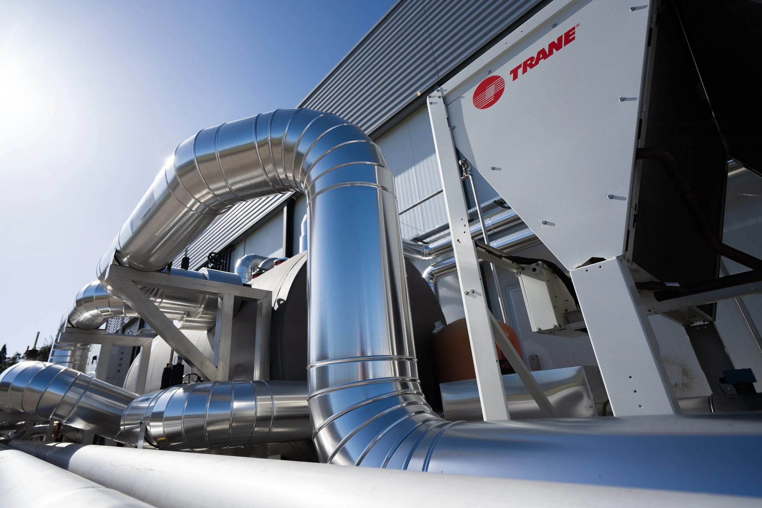 Installations industrielles avec des tubes en acier inoxydable et un gros équipement de refroidissement de la marque Trane, extérieur d'une usine ou centre de traitement