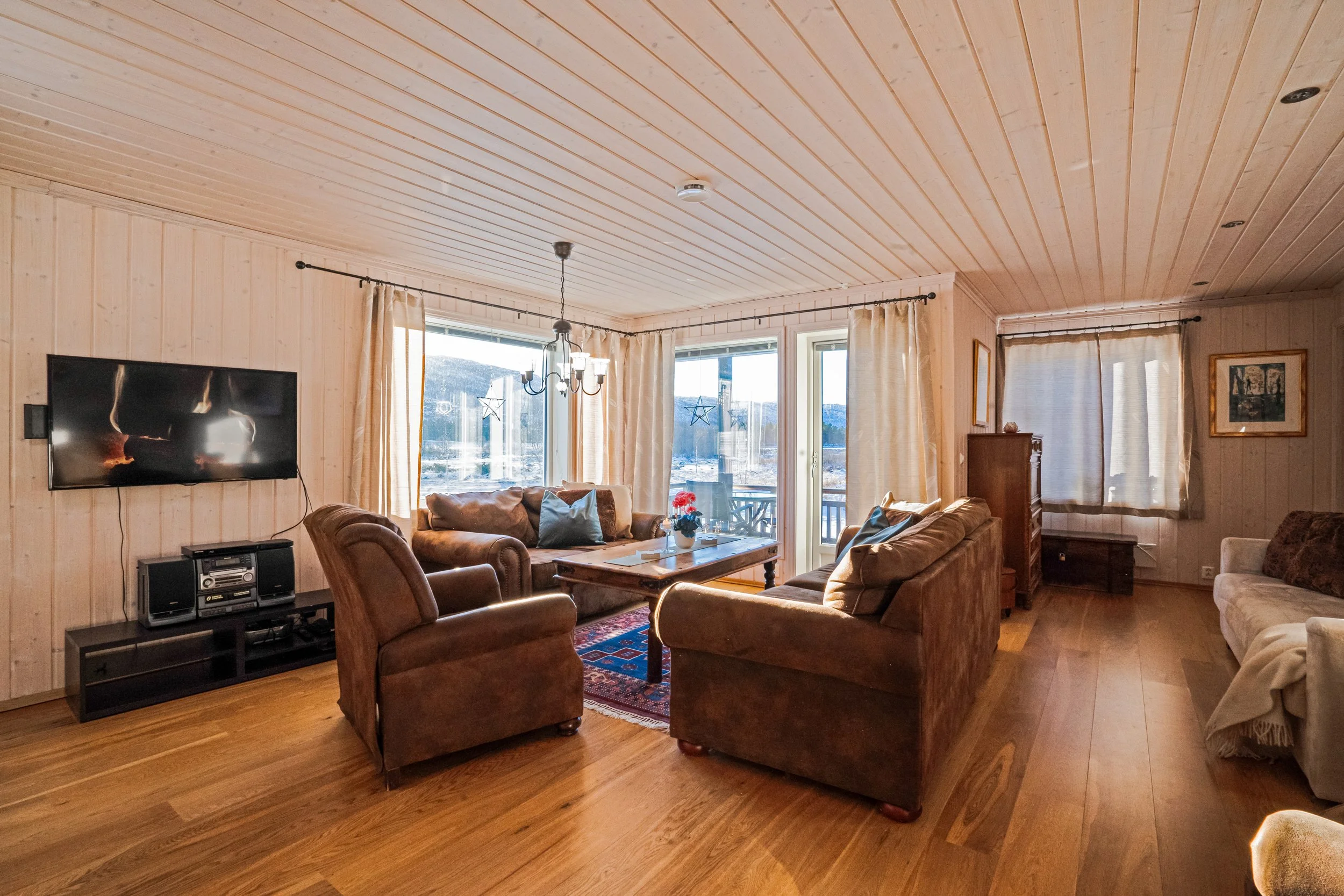 Sofagruppe i stue plassert foran store vinduer. Foto (Copy)