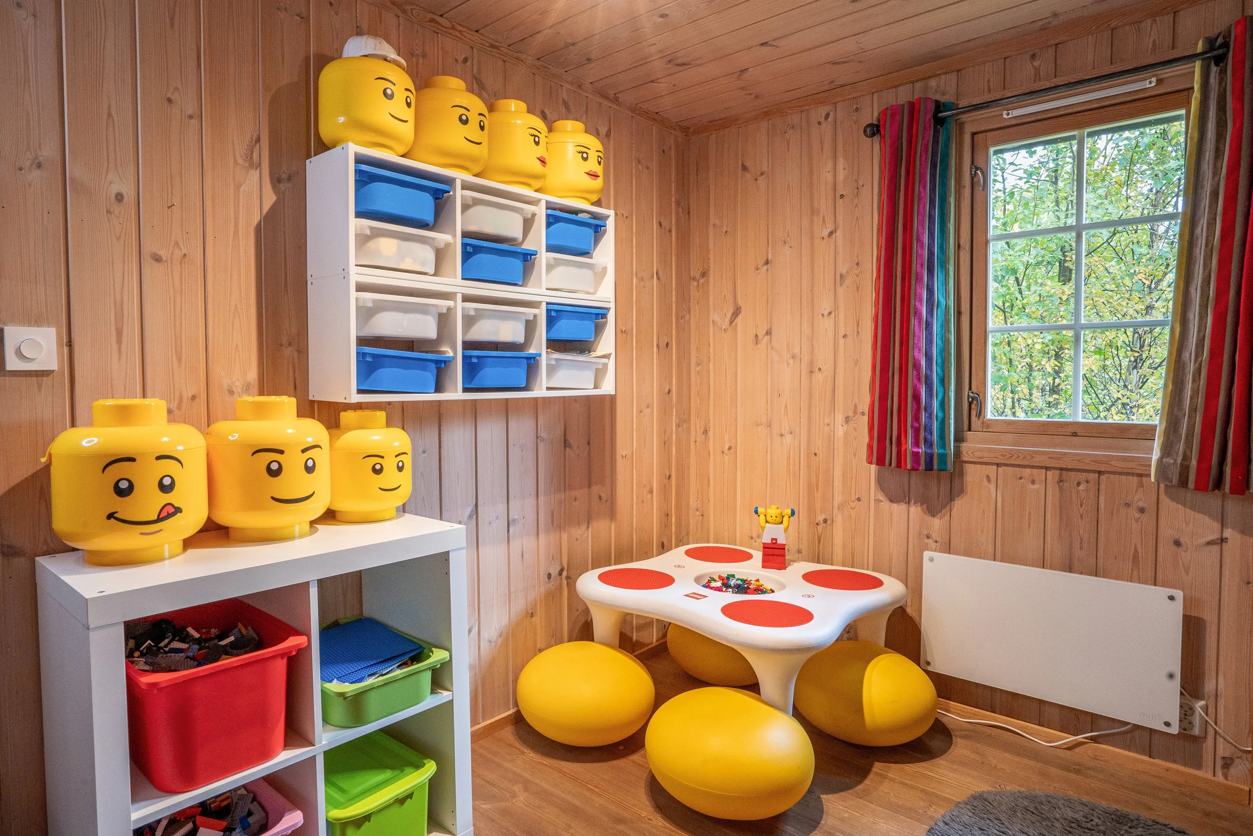 Rom med LEGO-byggebord, og hyller fylt med LEGO. Foto