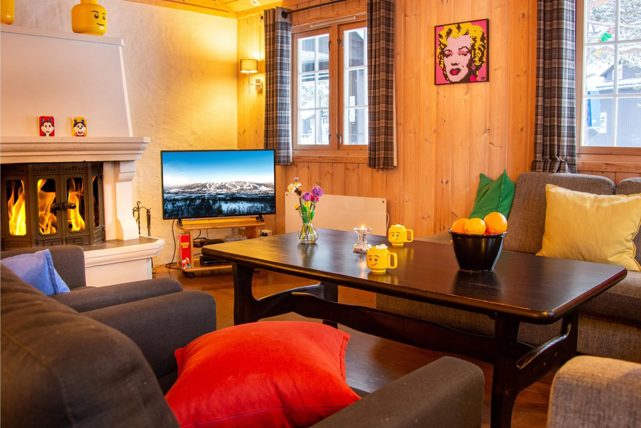 Stue med sofa, sofabord, peis og TV. Dekorert med diverse LEGO-detaljer. Foto