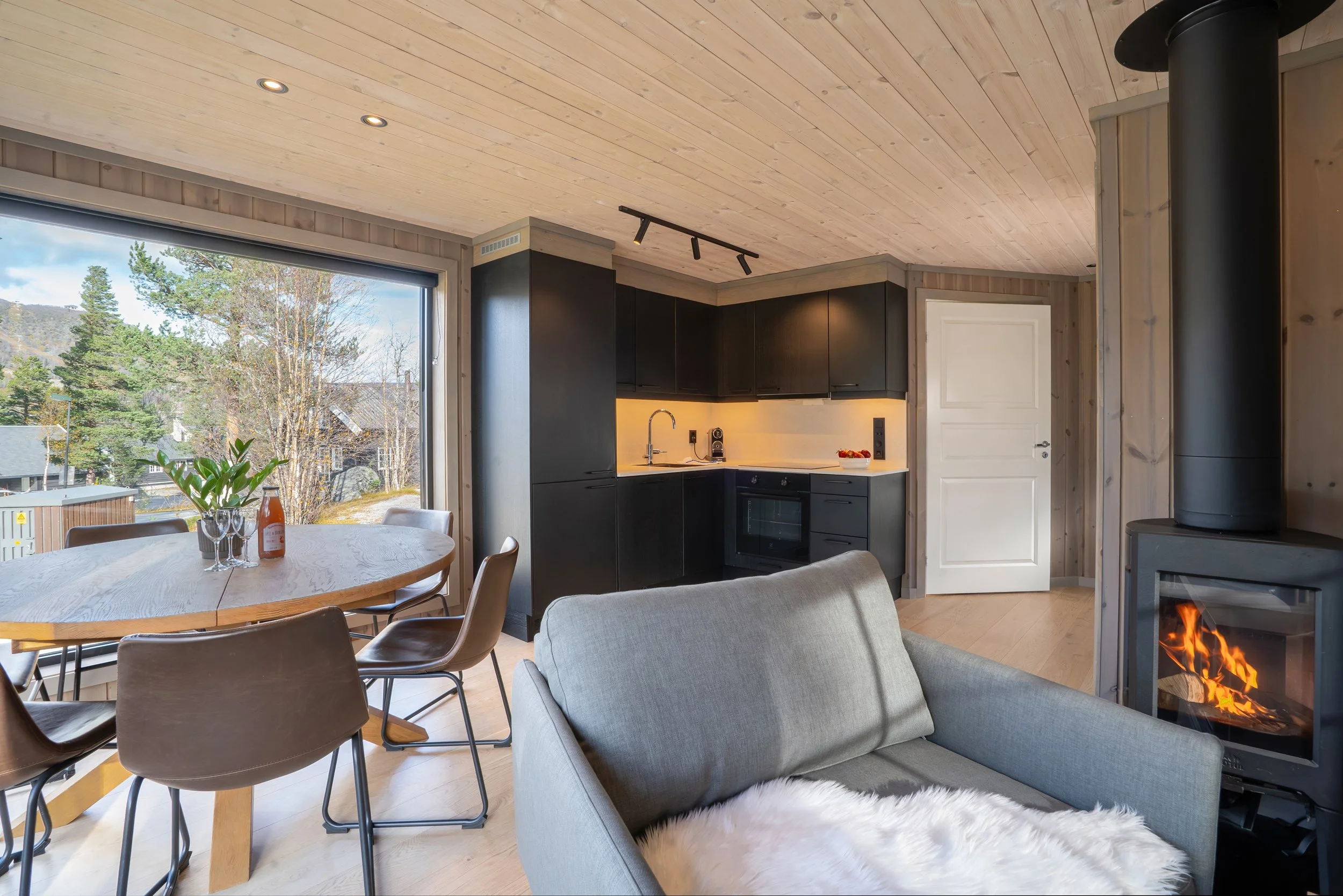 Moderne åpen stue- og kjøkkenløsning, med spisebord og peis. Foto