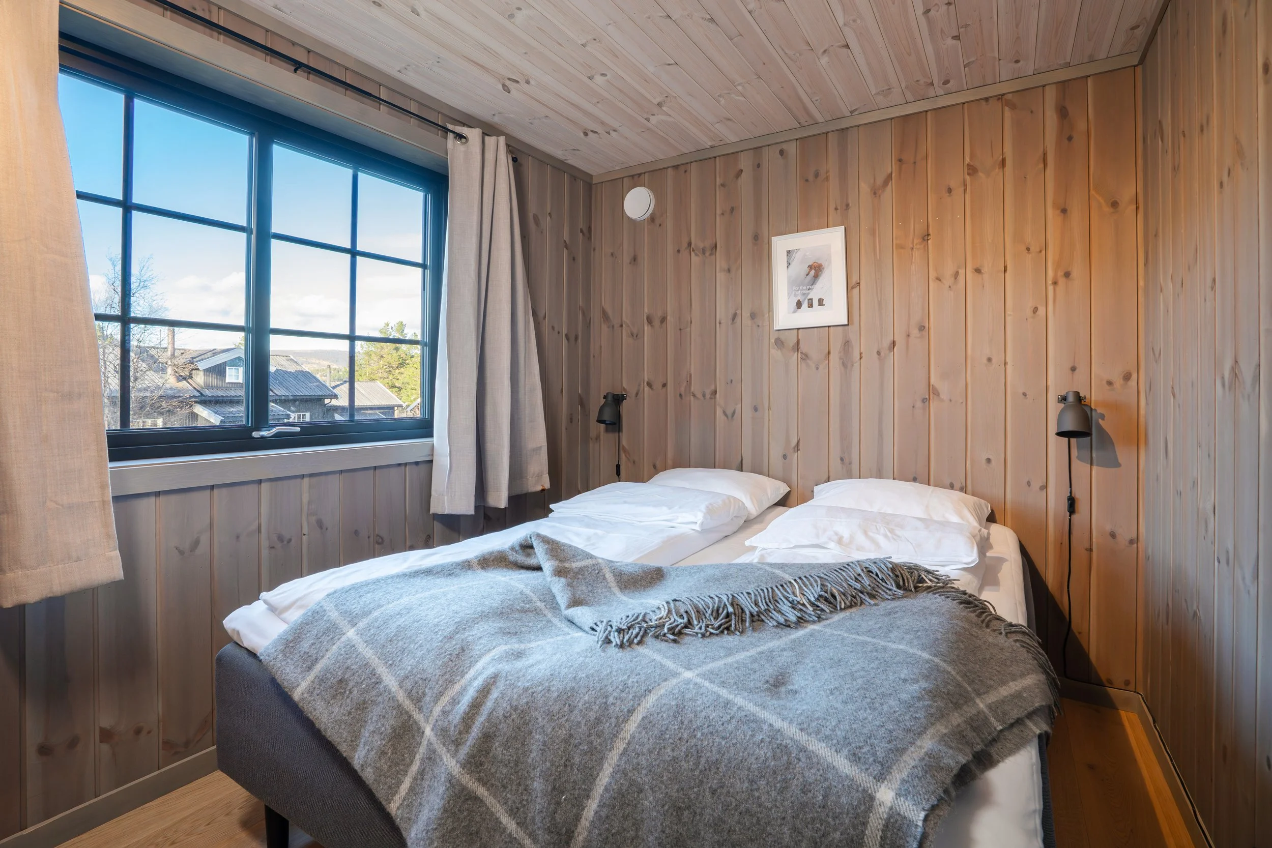 Soverom med oppredd dobbeltseng og stort vindu. Foto