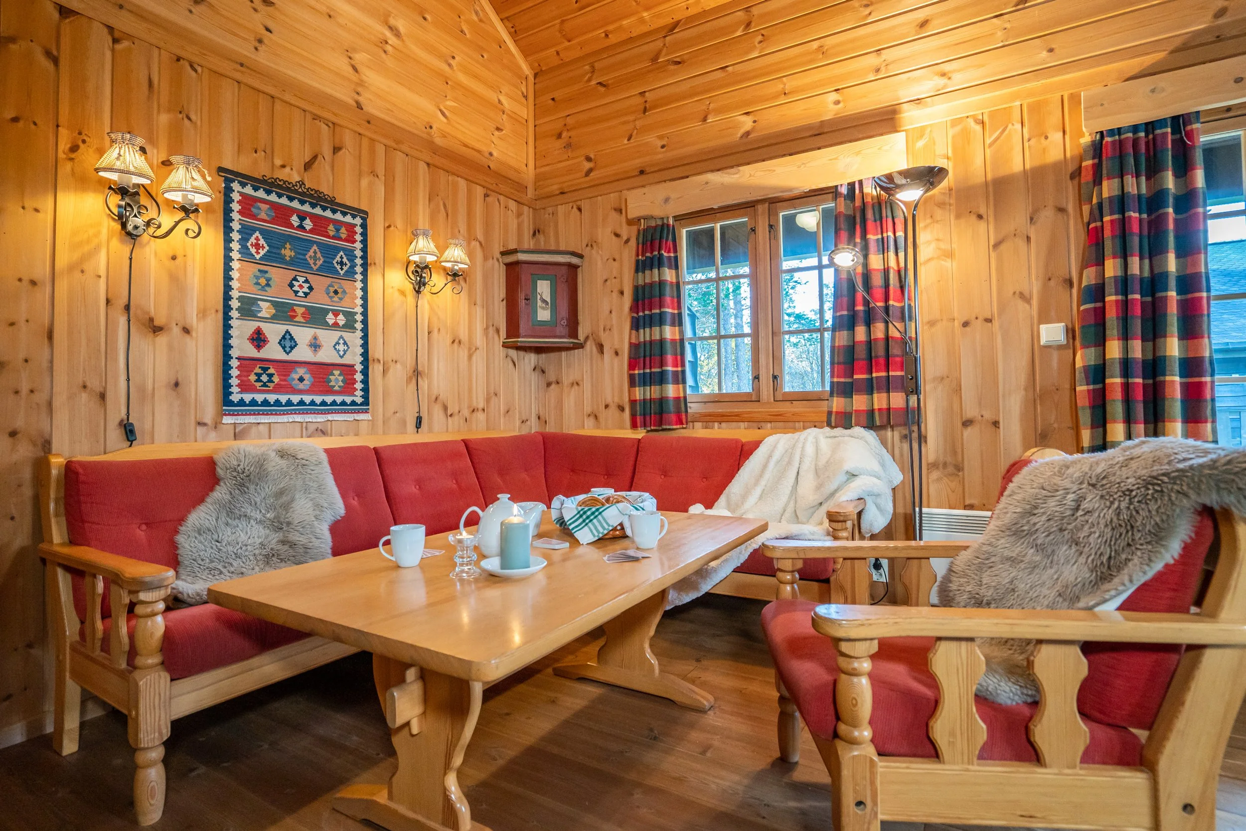 Stue i tradisjonell, norsk hyttestil. Kaffekopper og kurv med boller på bordet. Foto