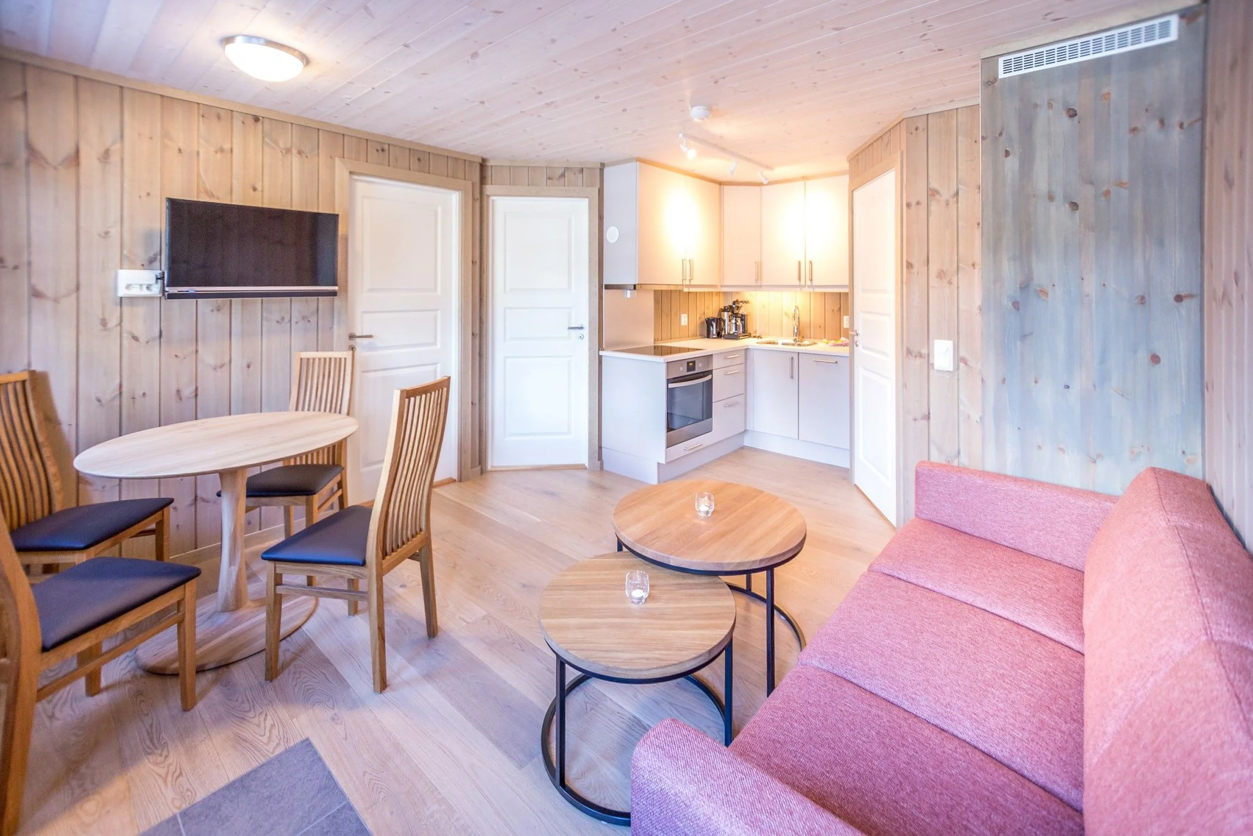 Leilighet med åpen stue- og kjøkkenløsning. Liten kjøkkenkrok, sofa med sofabord og spisestue. Foto