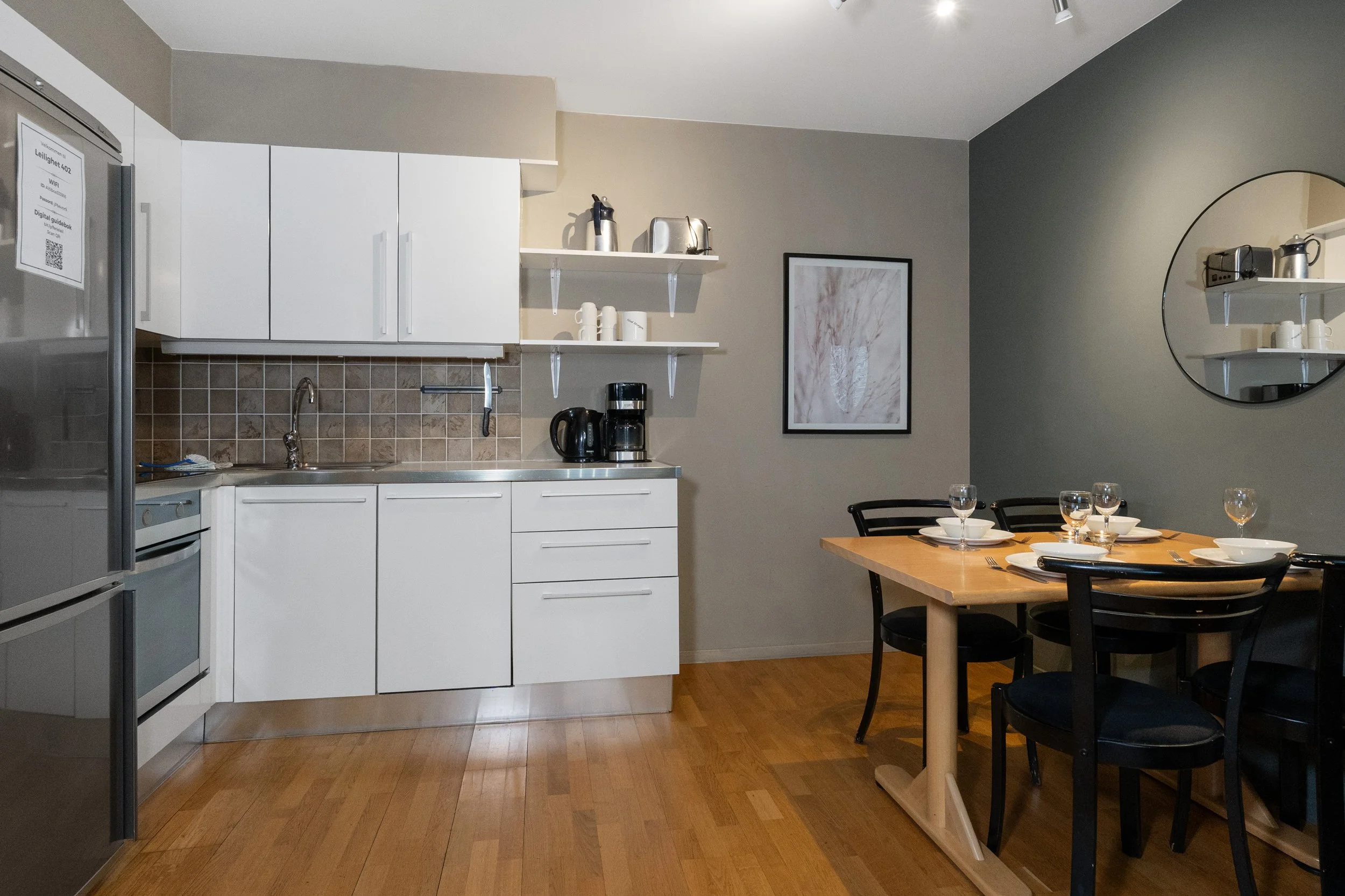 Kjøkken i moderne farger. Pådekket spisebord. Speil og bilde henger på veggen. Foto