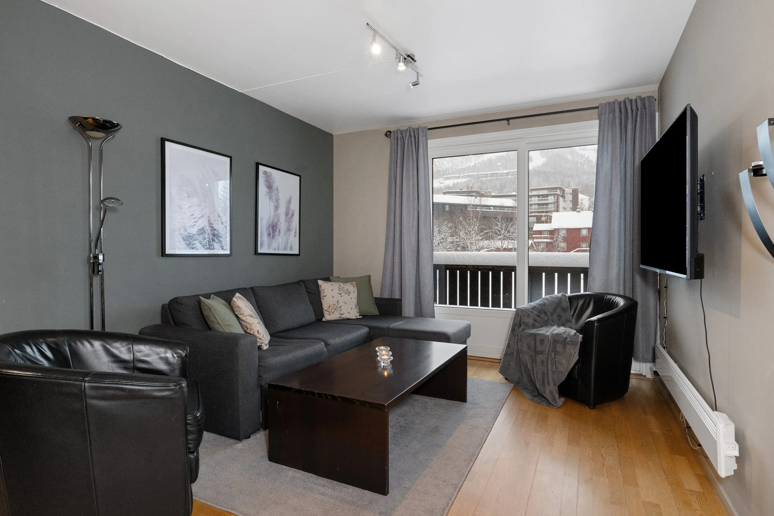Stue med stol, sofa, sofabord og tv. Stort vindu, og terrassedør. Foto