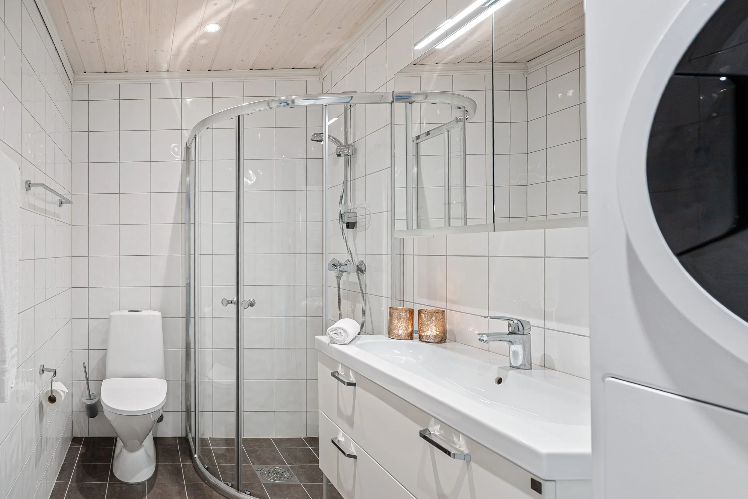 Bathroom with toilet, shower, washing machine and dryer. Photo