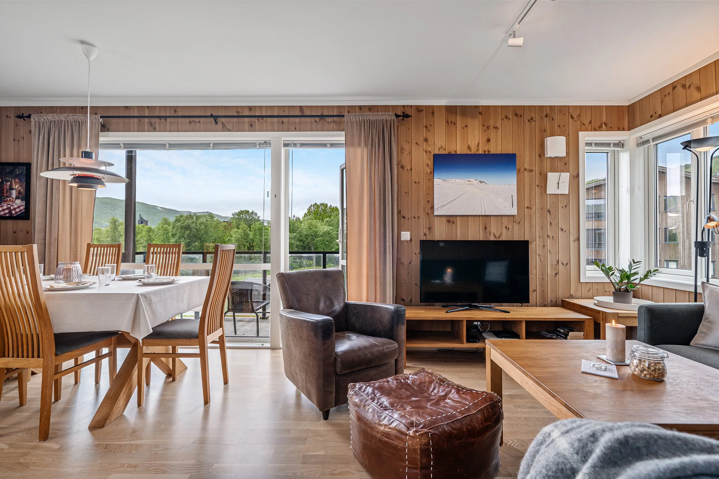 Nicely decorated living room and dining room. View of green trees. Photo