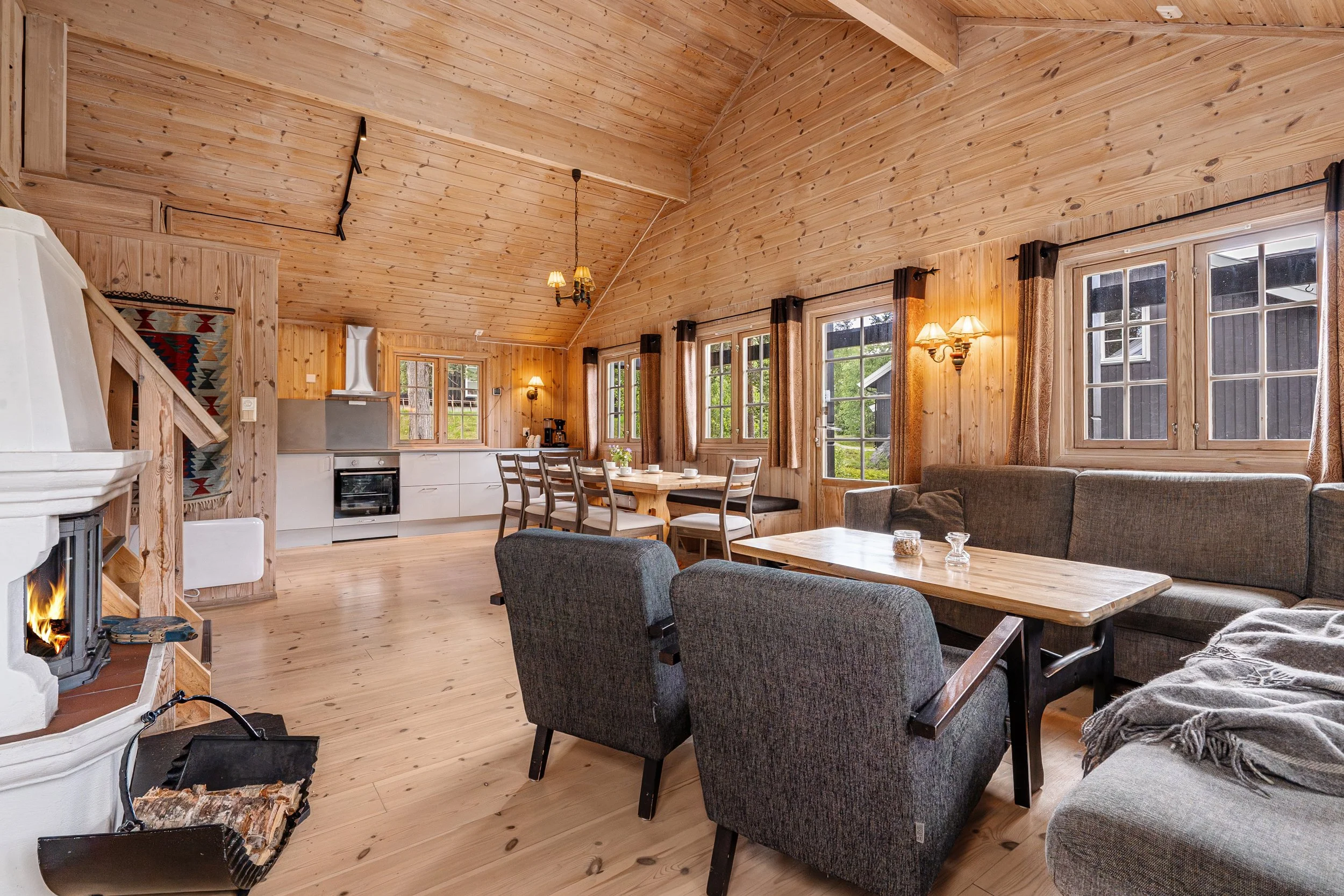 Large open living room and kitchen. Fireplace, set dining table, and cozy sofa area. Photo