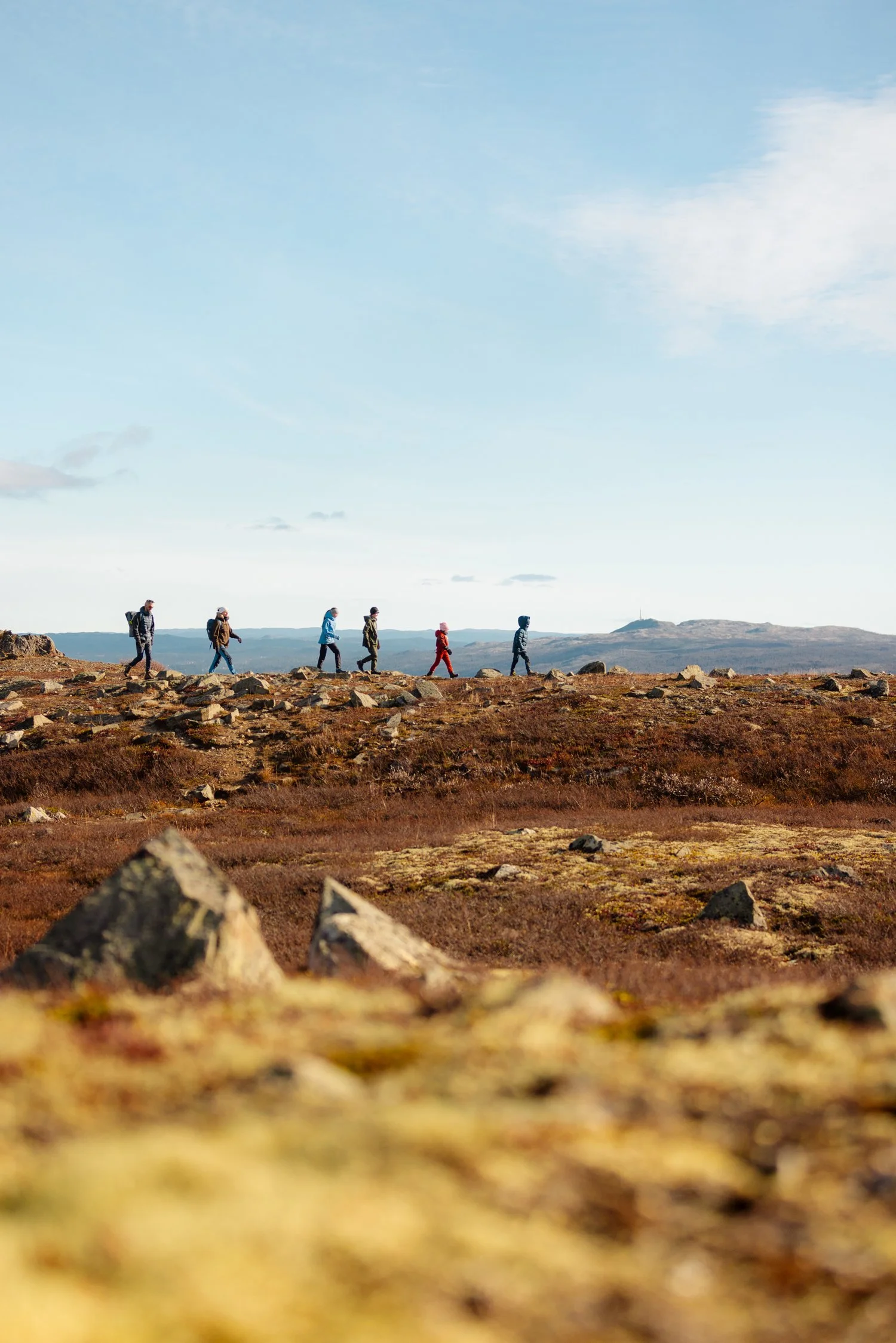 Mennesker går over en fjellrygg i høstlandskapet.
