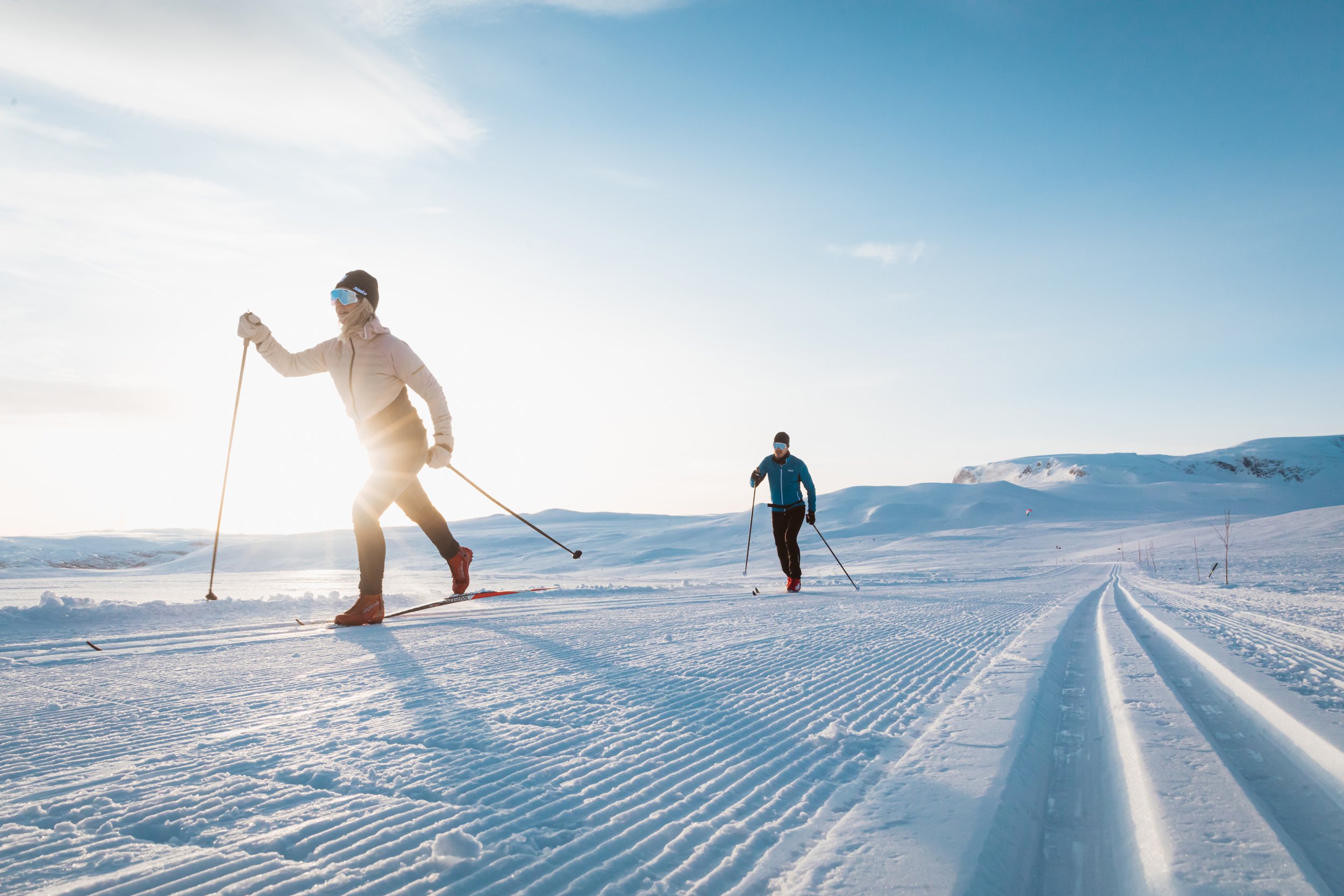 To personer går på skitur på fjellet i nypreppa løyper.