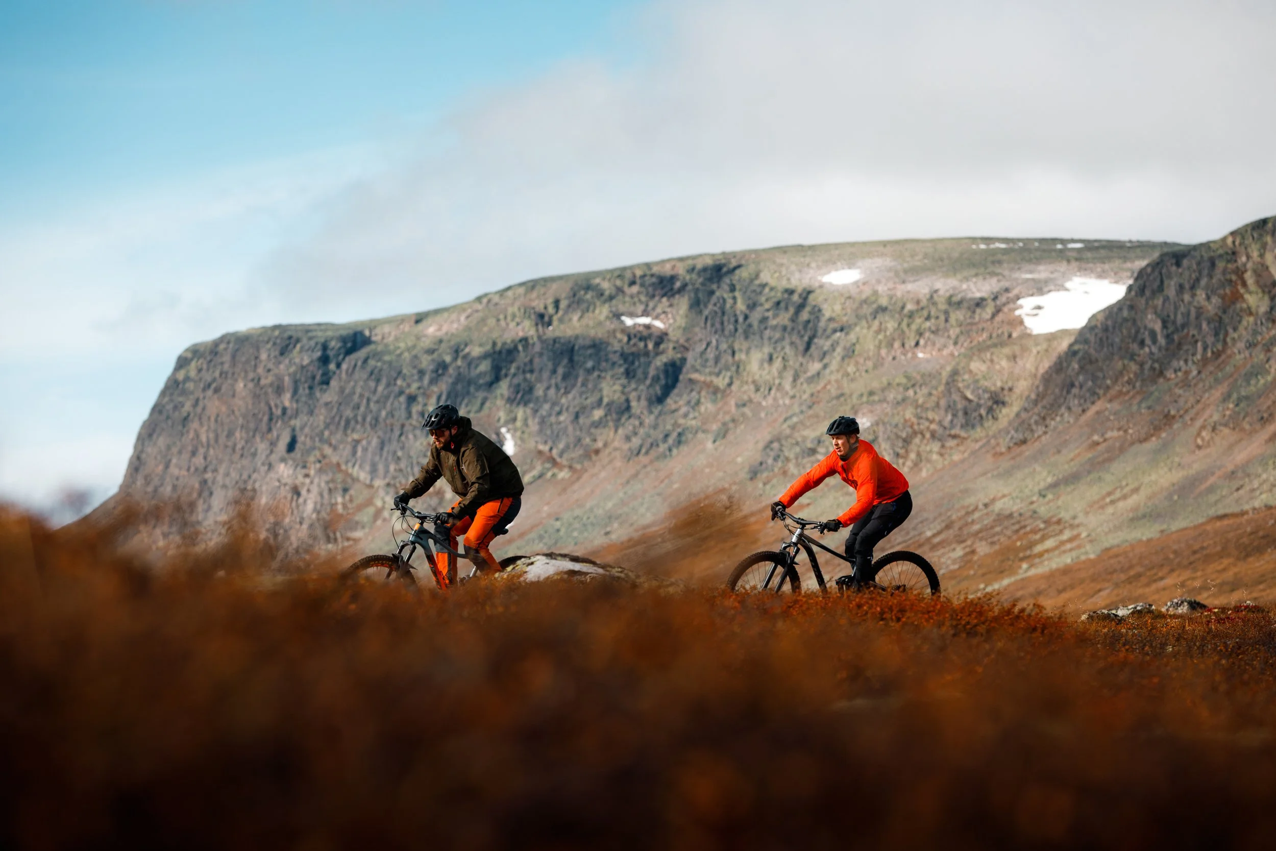 To personer sykler i høstlandskap på høyfjellet.
