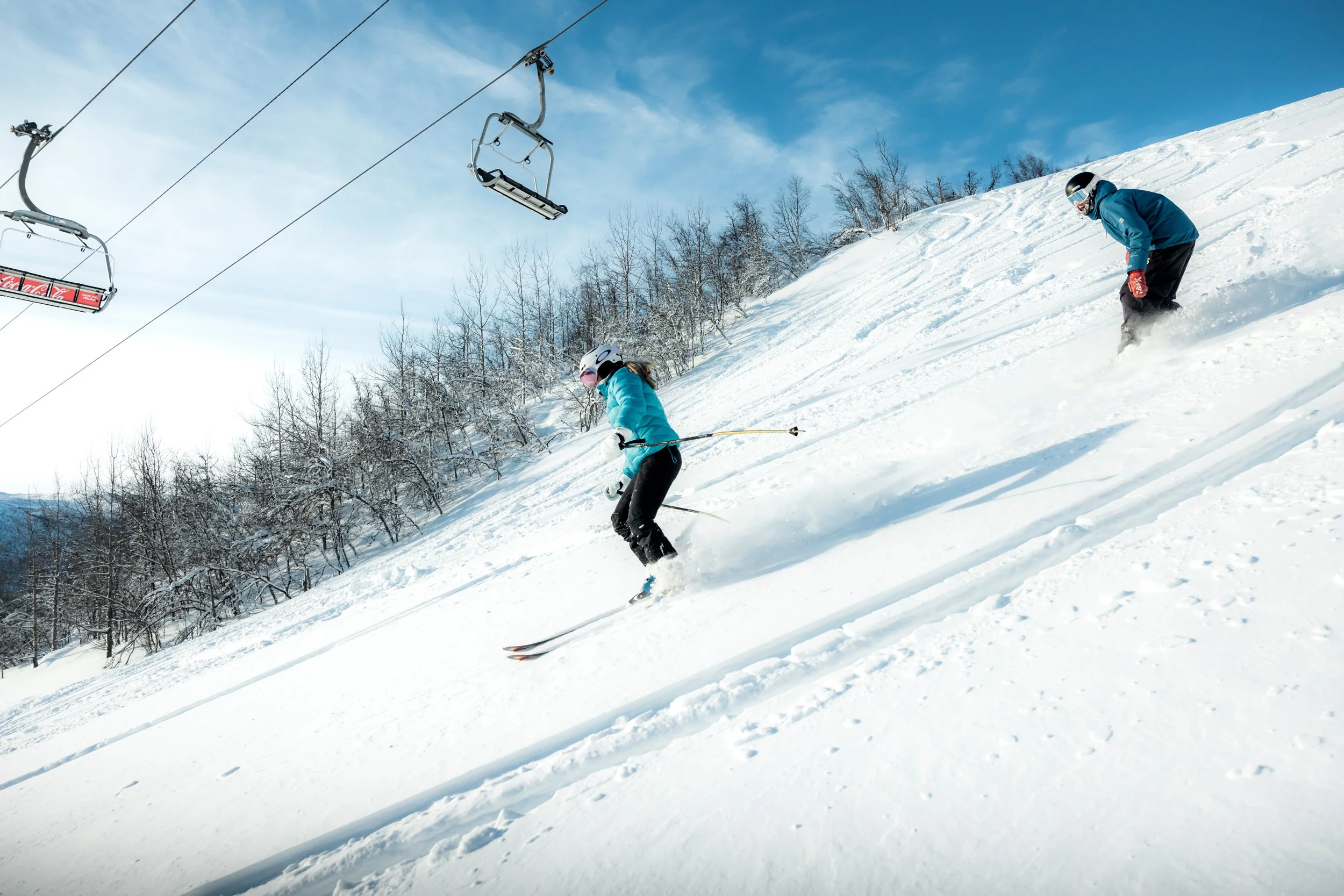 Jente står på slalom i pudderføre med skiheisen over.
