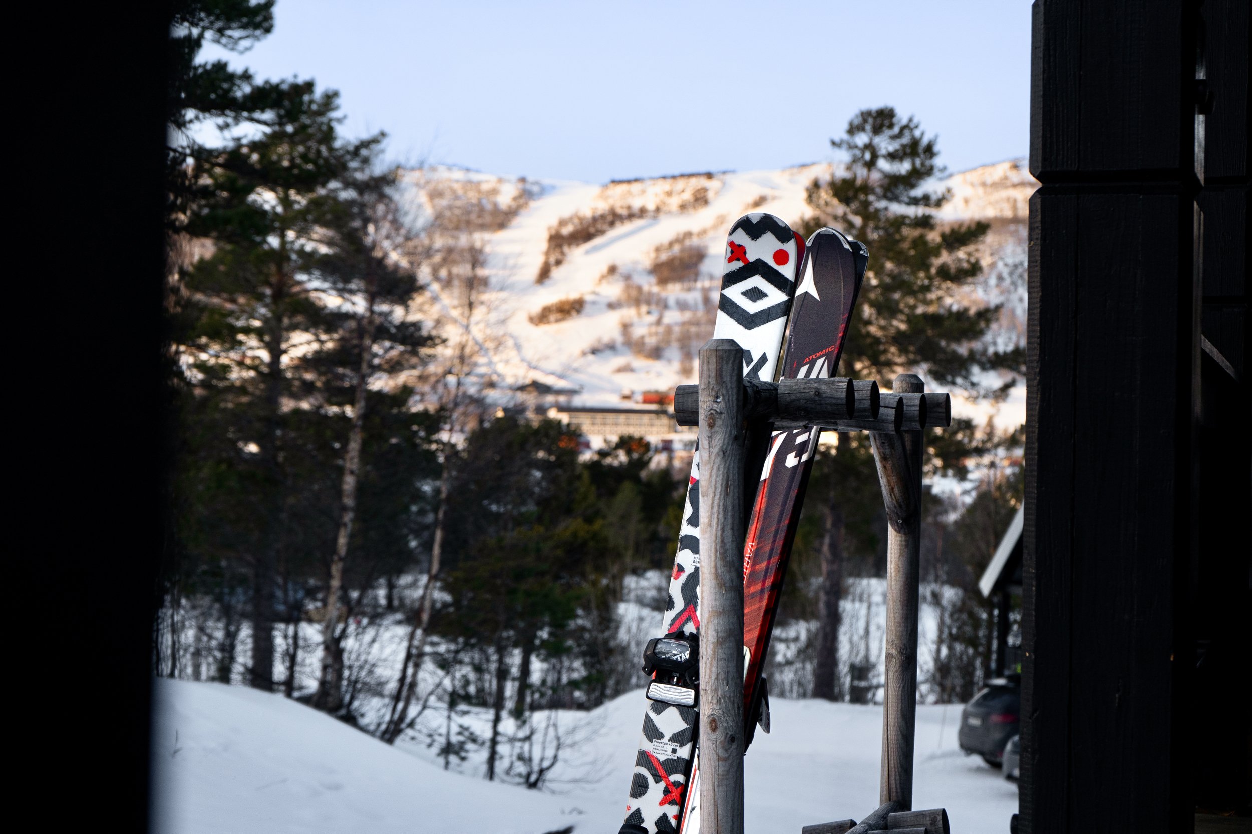 Ski i skistativ med skibakke i bakgrunnen.