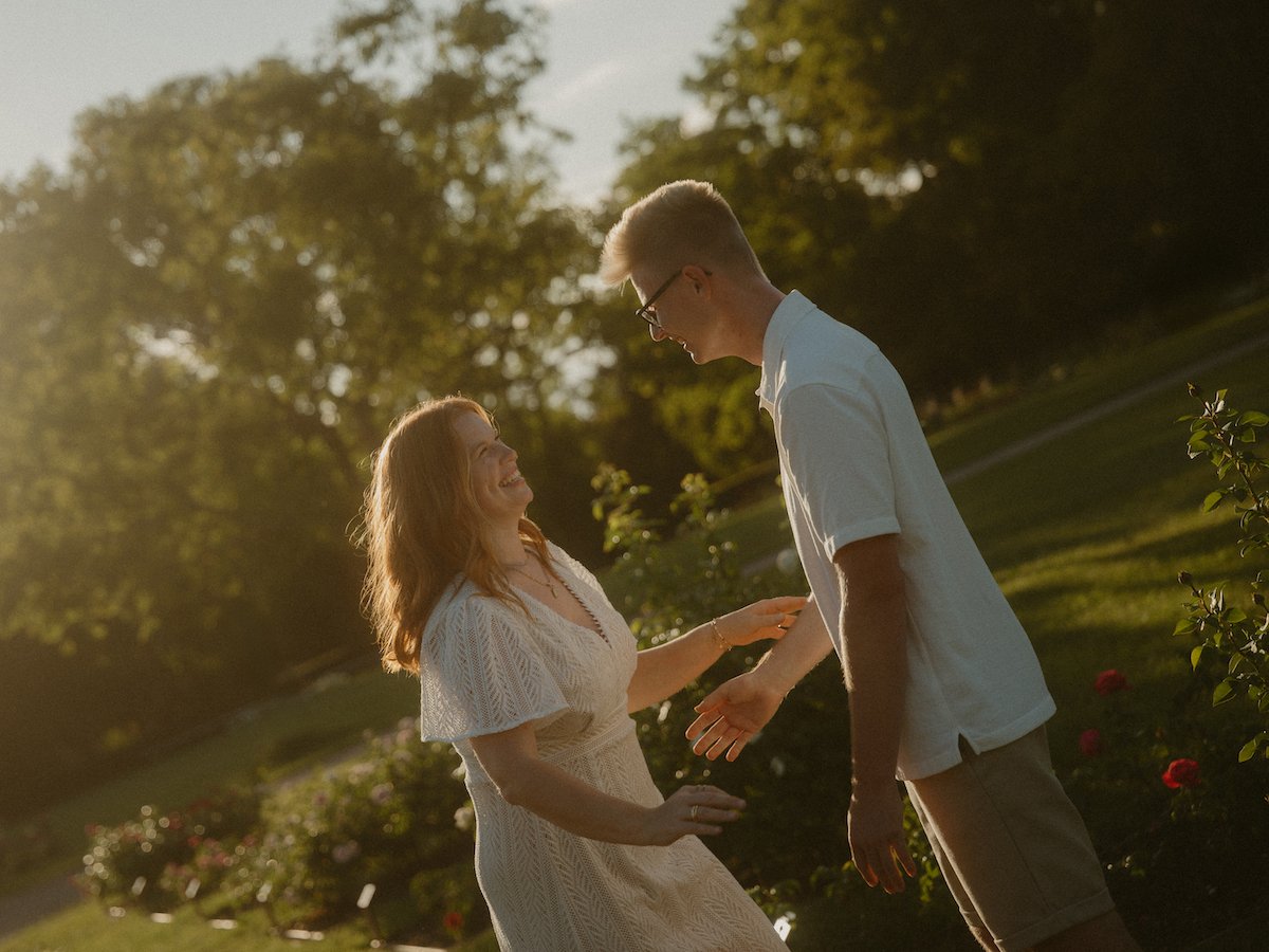 Ein Paar lacht sich ausgelassen auf der Rosenhöhe in Darmstadt an, vor einem schönen Sonnenuntergant