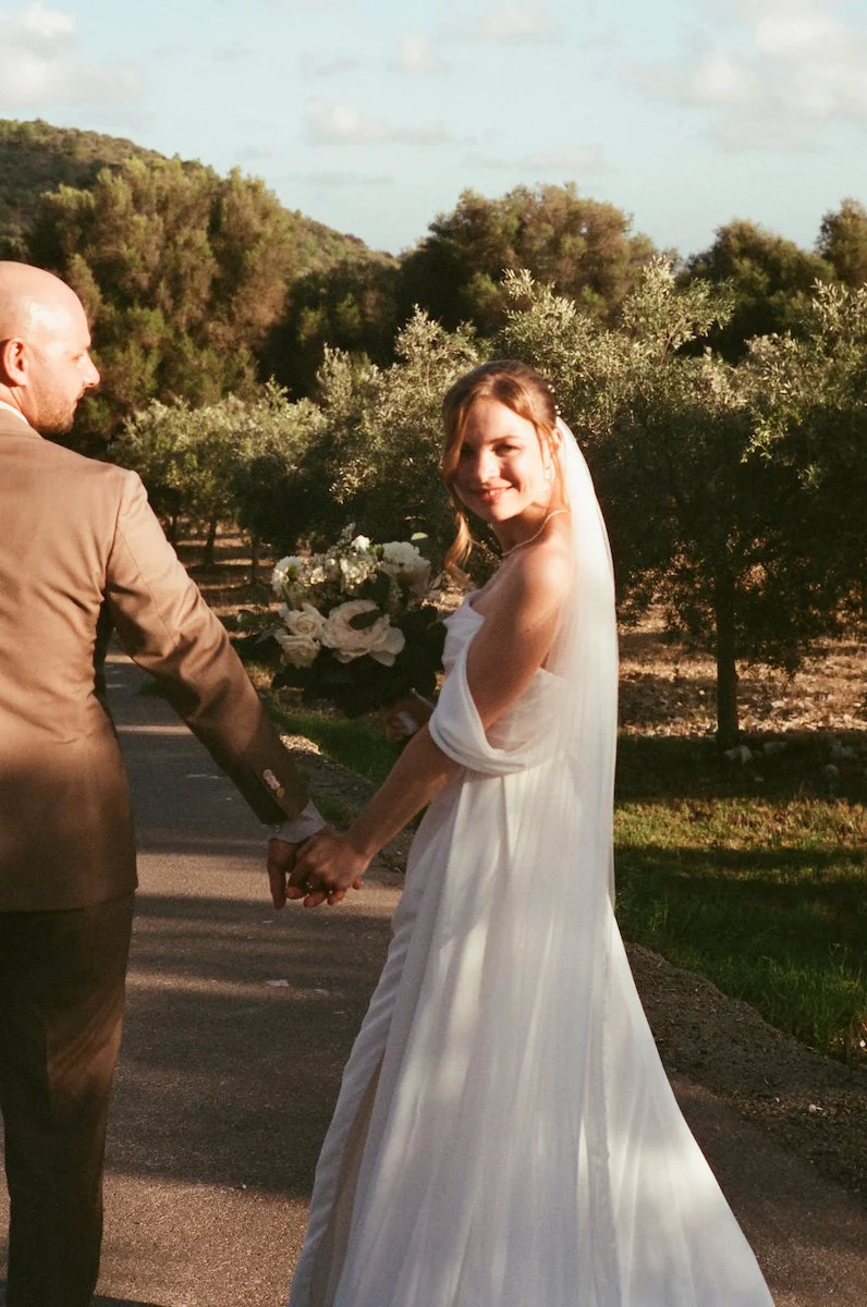 Analoge Hochzeitsfotografie einer freie Trauung auf der Finca ses Voltes auf Mallorca, Braut und Bräutigam Hand in Hand zwischen Olivenbäumen im warmen Abendlicht