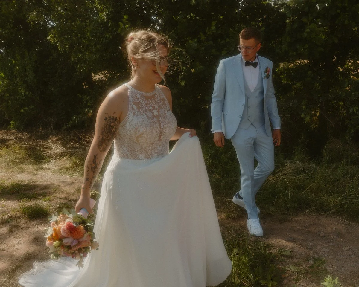 Die Braut schreitet lächelnd voran, begleitet vom Bräutigam nach der freien Trauung für ihre Hochzeitsfotos in Darmstadt.