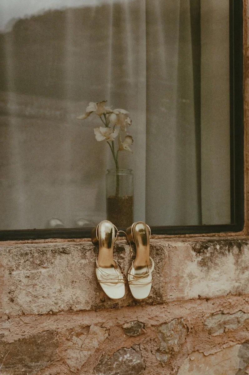 Detailaufnahme von goldenen Brautschuhen, die vor einer Destination Wedding in einem Fenster der Finca ses Voltes auf Mallorca hängen
