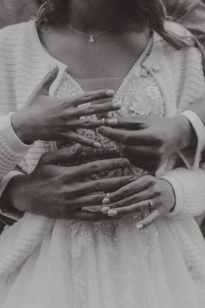 Leiser, inniger Moment festgehalten vom Hochzeitsfotograf aus Darmstadt: Mehrere Hände liegen schützend auf dem Brautkleid und zeigen Nähe und Verbundenheit in Dieburg.