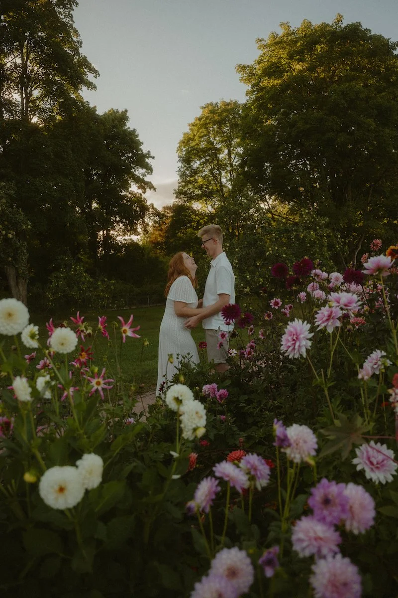 Ein verliebtes Paar beim Verlobungsshooting auf der Rosenhöhe in Darmstadt, umgeben von Blumen und Abendlicht