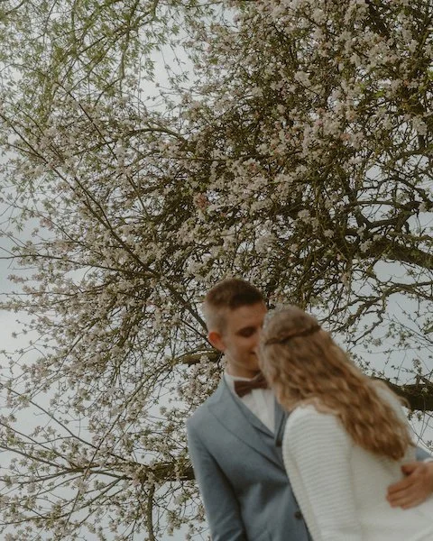 Ein Brautpaar steht sich innig unter blühenden Bäumen am Restaurant Grünewalds in Otzberg gegenüber, begleitet von einem Hochzeitsfotograf aus Darmstadt.