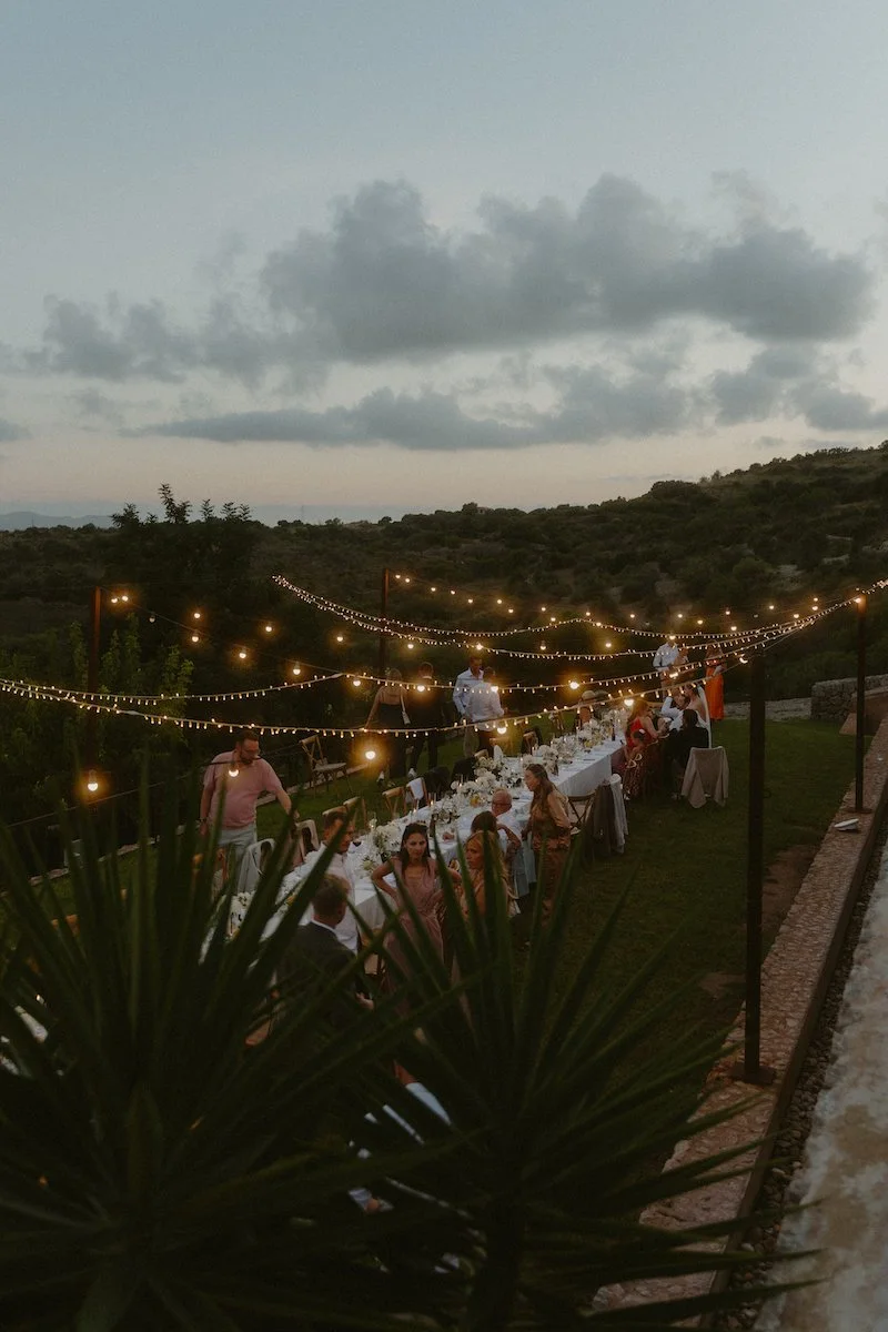 Lichterketten am Abend über einem langen Esstisch, an dem die Hochzeitsgesellschaft nach der Destination Wedding auf Mallorca feiert