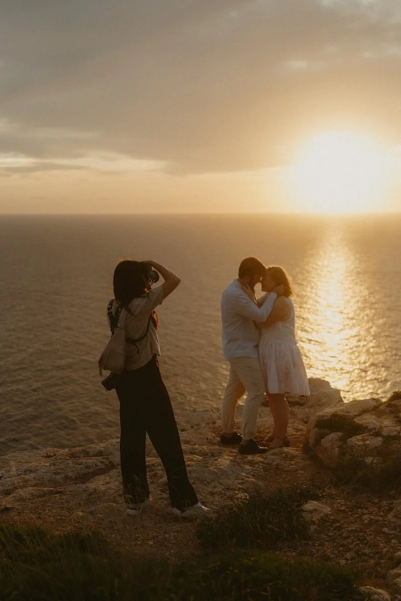 Eine Destination Wedding Fotografin fotografiert auf Mallorca vor dem Sonnenuntergang über dem Meer ein vertrautes Hochzeitspaar