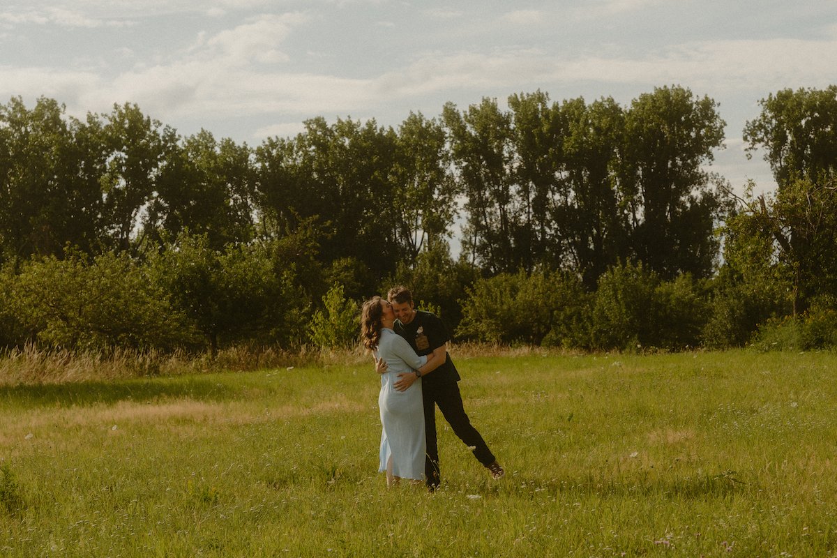 Ein Paar werdender Eltern umarmt sich glücklich auf einer grünen Wiese in Dreieich.