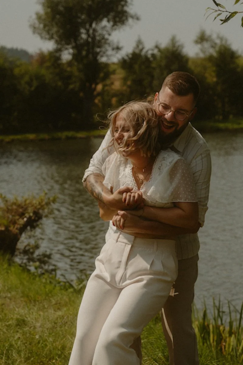 Ein ausgelassenes Brautpaar beim Umarmen am Ufer des Hahner Sees während ihrer Hochzeitsreportage nahe Darmstadt.