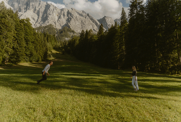 Ein verliebtes Paar läuft sich beim Verlobungsshooting am Eibsee in Garmisch-Partenkirchen entgegen, ein natürliches Fotoshooting voller Leichtigkeit und Nähe.