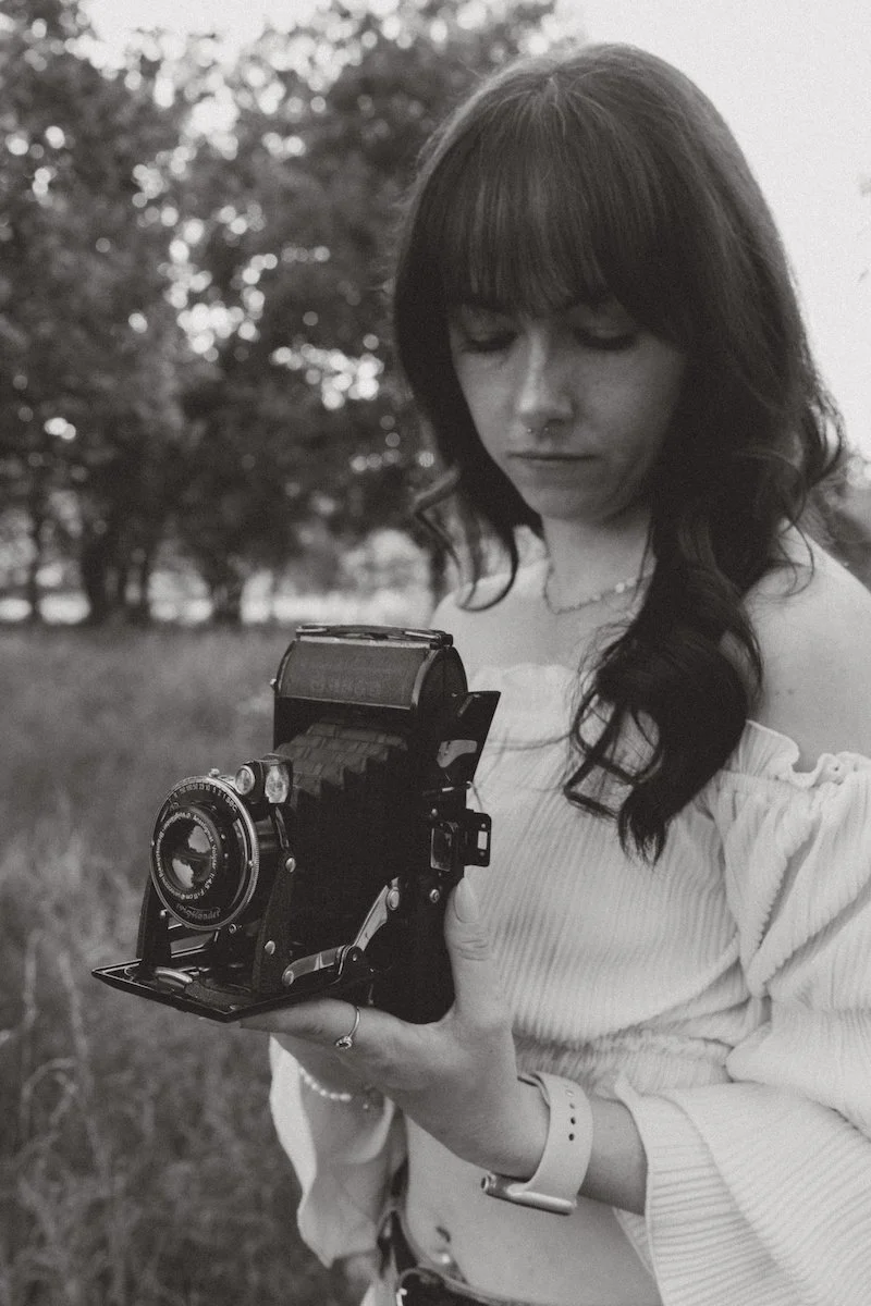 Eine Fotografin mit historischer analoger Kamera am Mainzer Sand in Mainz, ruhig und konzentriert bei persönlicher fotografischer Arbeit in Schwarzweiß