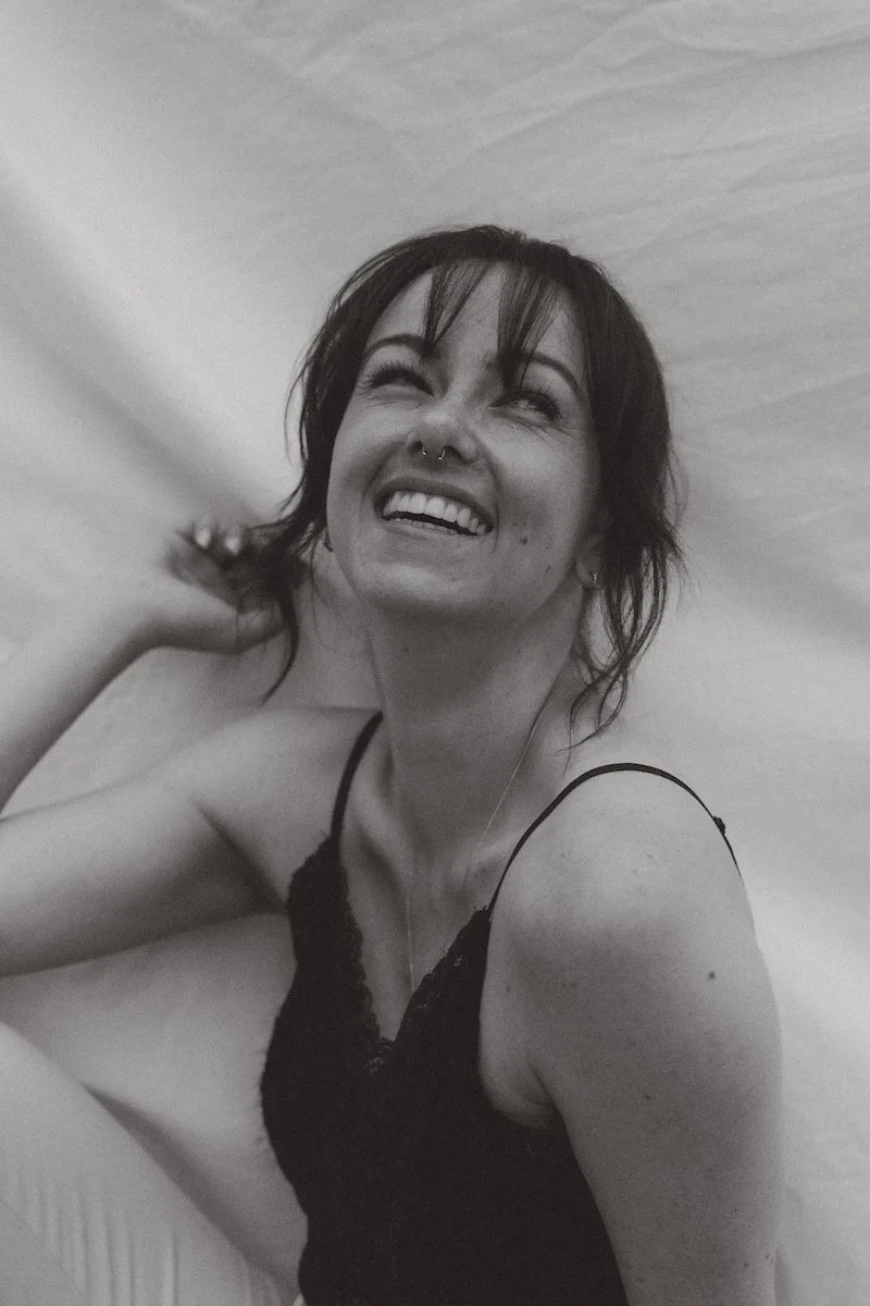 Schwarzweißes Portrait einer Hochzeitsfotografin, die lächelnd in den Himmel schaut