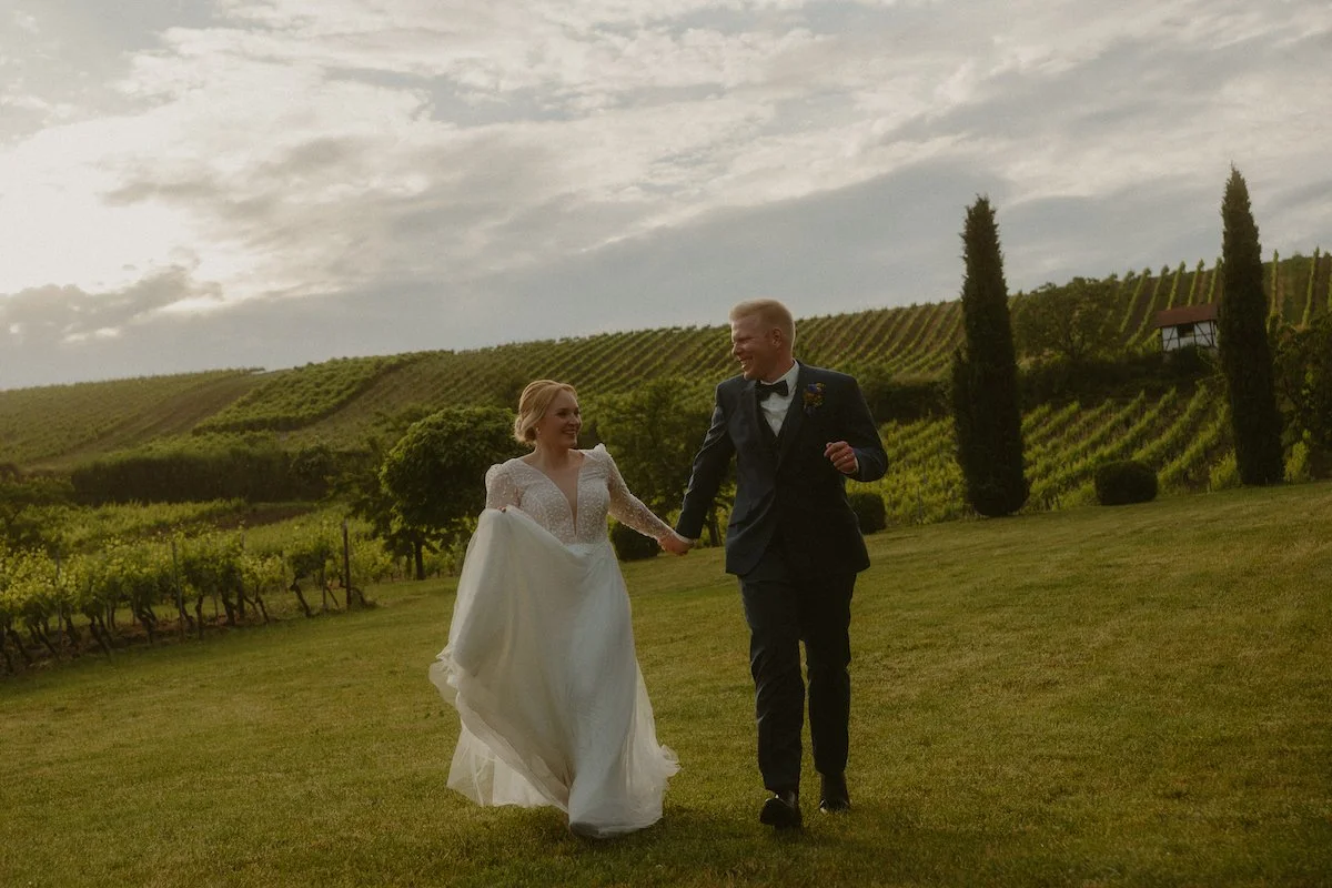 Brautpaar läuft Hand in Hand über die Wiesen des Hofgut Donnersberg in Vendersheim nach einer kirchlichen Trauung, festgehalten in einer natürlichen Reportage