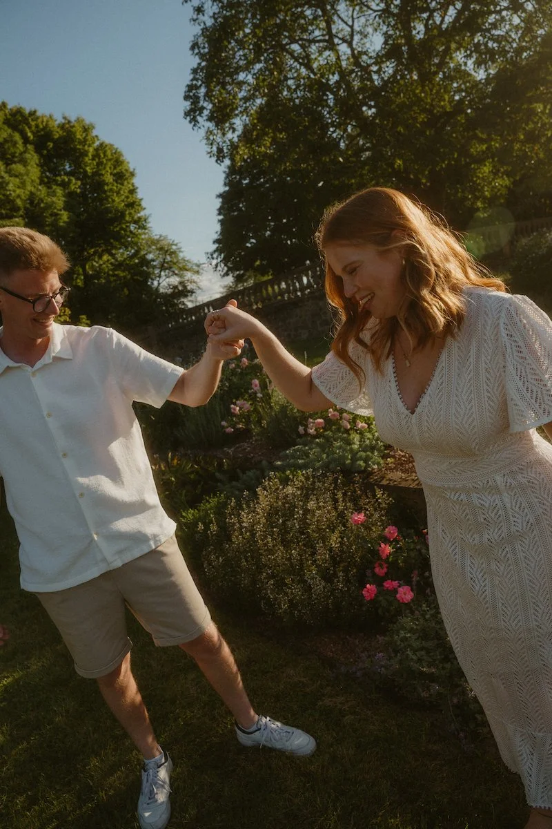 Ein glückliches Paar tanzt Hand in Hand durch die Rosenhöhe in Darmstadt, eingefangen bei einem natürlichen Fotoshooting in Darmstadt voller Nähe und Freude.