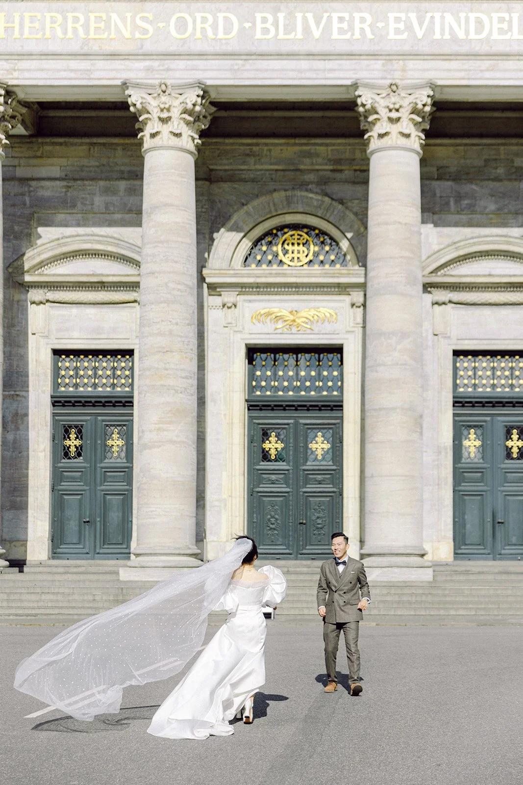 Bride and groom walking in front of the frederiks church veil flying in the wind romantic elegant denmark copenhagen.jpg