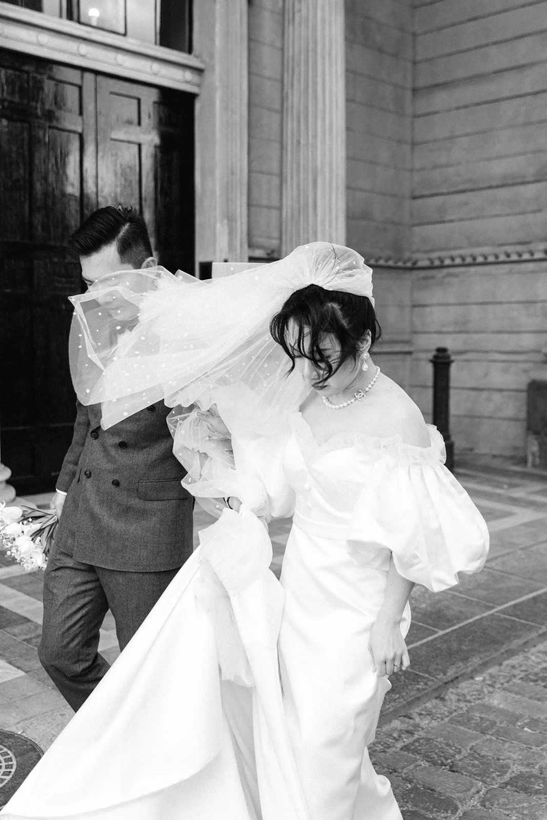 Bride and groom walking in amalienborg slot veil flying in the wind romantic elegant in denmark copenhagen.jpg