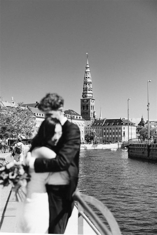 Bride and groom walking by canal in copenhagen denmark bride in white suit christiansborg slot.jpg