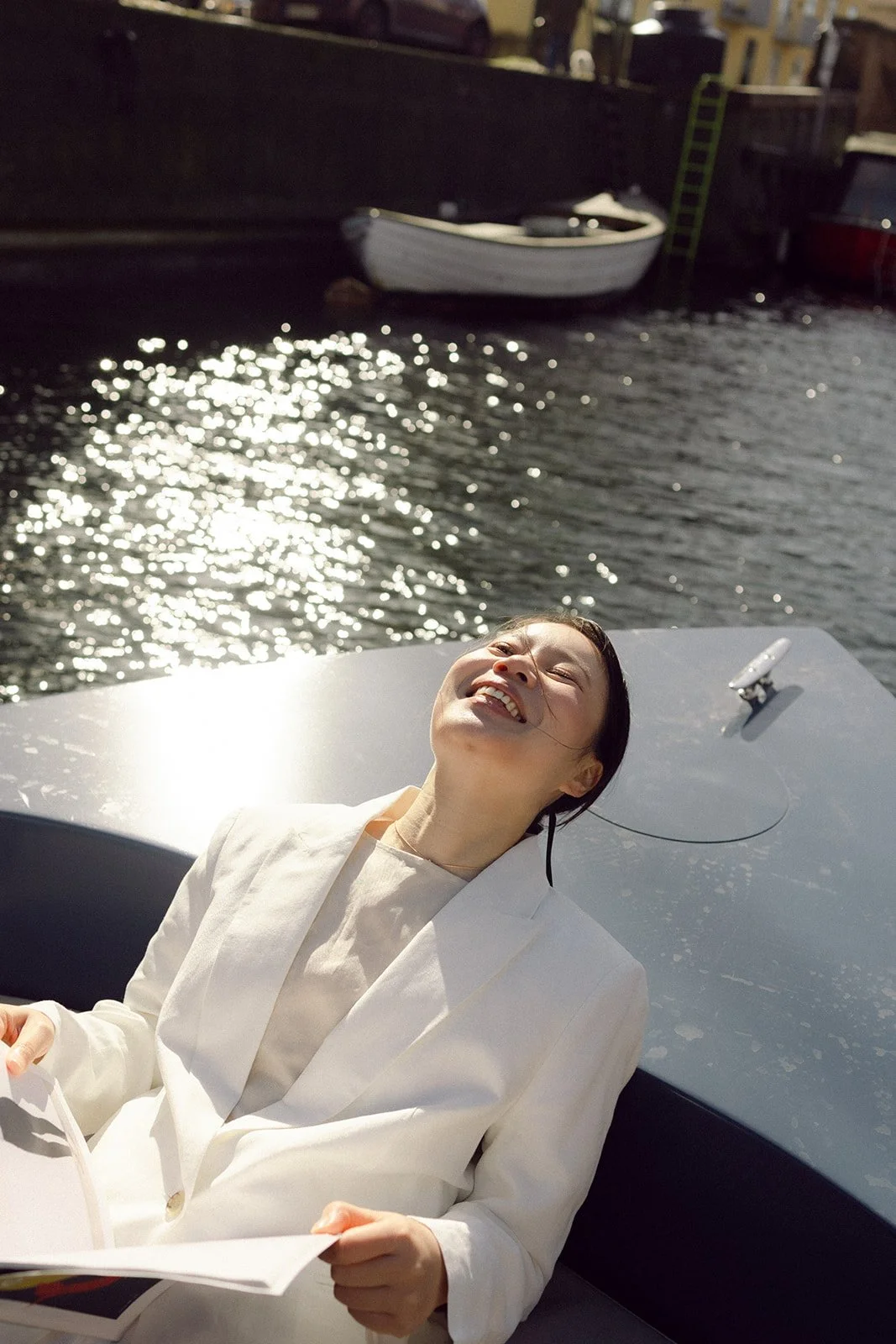 Bride laughing portrait on a goboat in a sunny day in canal in copenhagen.jpg