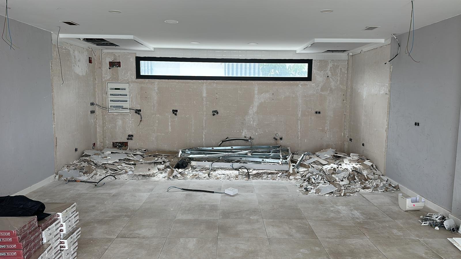 Room under renovation with exposed drywall, construction debris, and tools on the floor.