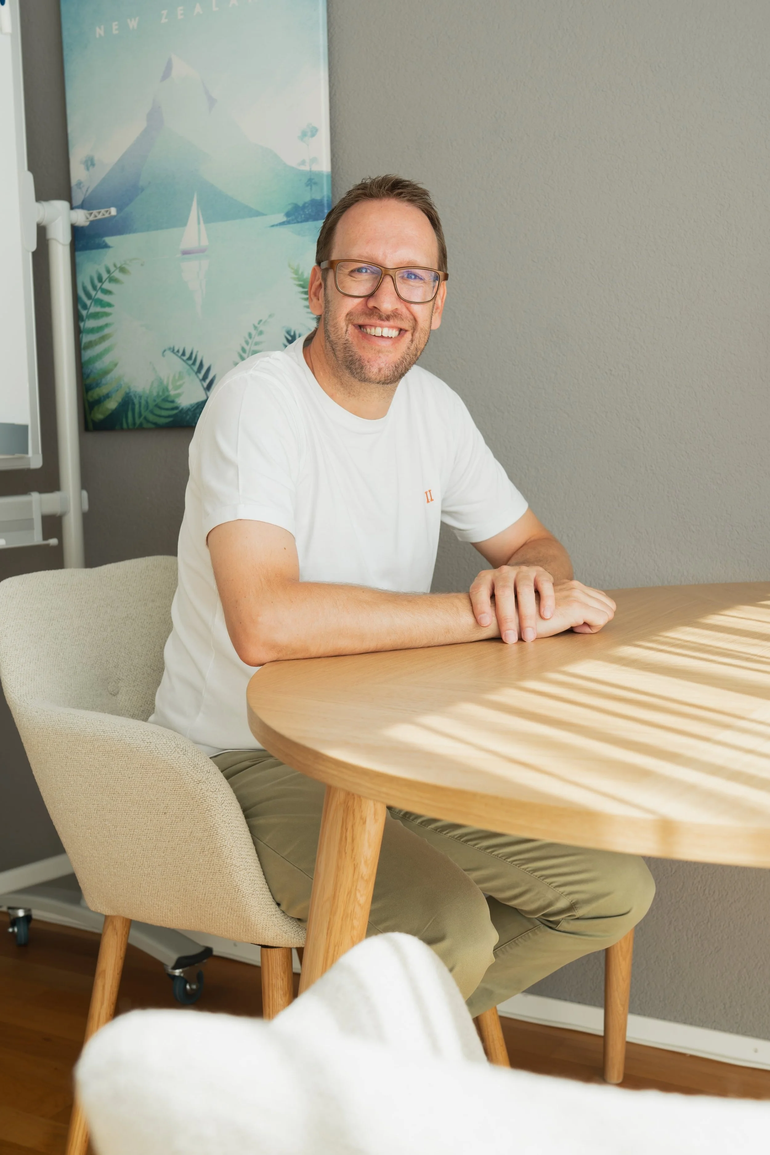 Matter sitzt lächelnd am runden Tisch im Coaching Raum – Coaching auf Augenhöhe in Hindelbank.