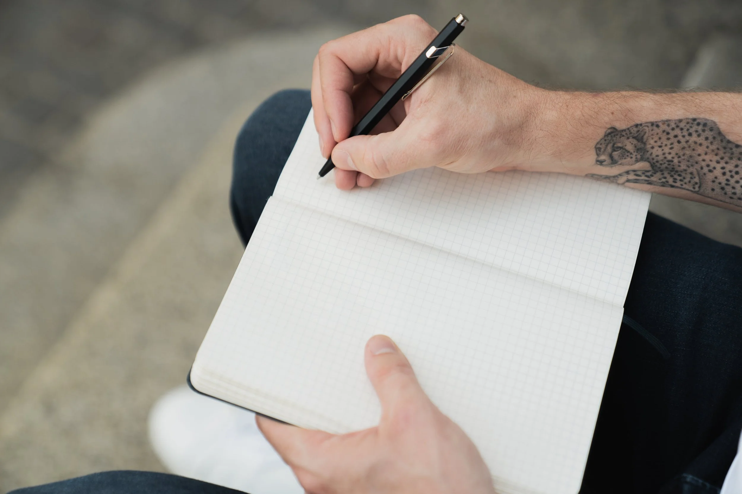 Hände mit Stift über einem leeren Notizbuch – der eigene Weg beginnt mit dem ersten Schritt.