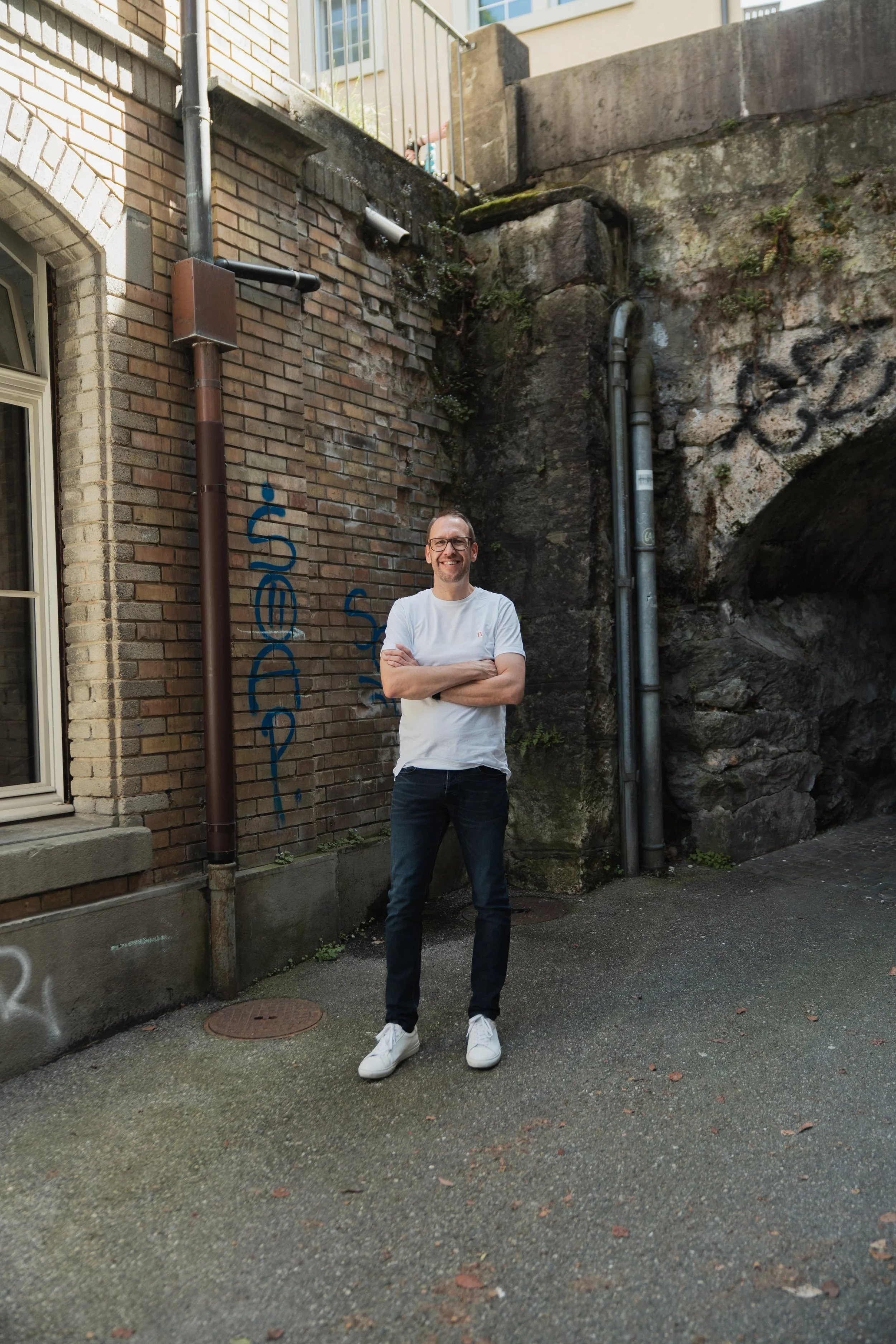Mike Matter, Co-Active Coach aus Hindelbank, steht entspannt vor einer Backsteinmauer – Coaching auf Augenhöhe, auch online.