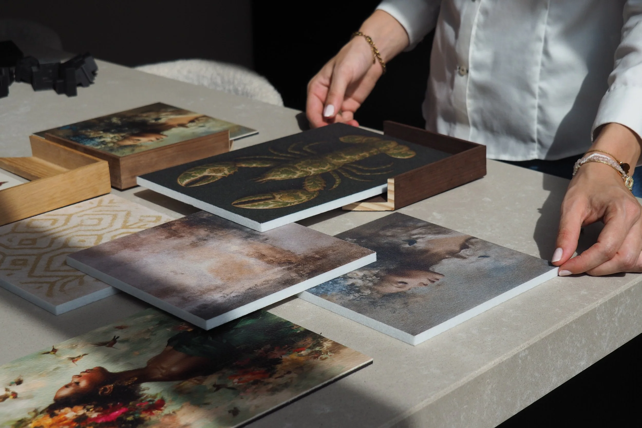 Person arranging decorative panels with images of animals and landscapes on a table.