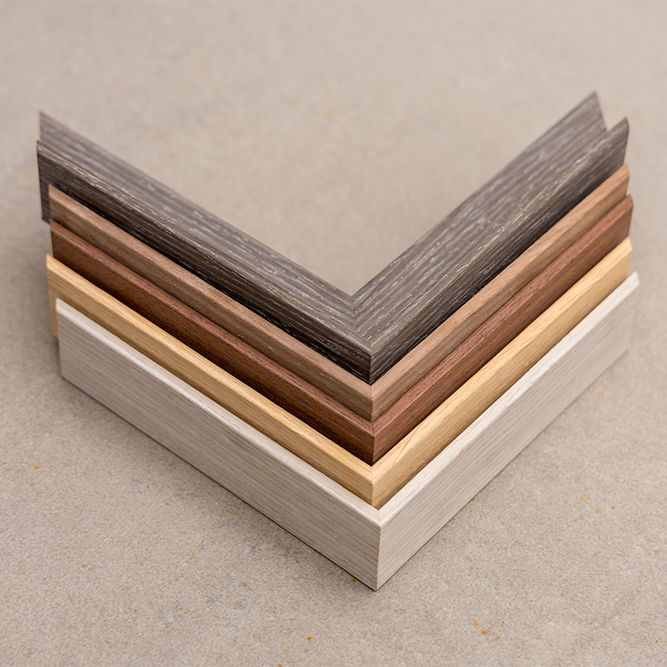Stacked sample wood corner molding in gray, dark brown, medium brown, light beige, and off-white colors.