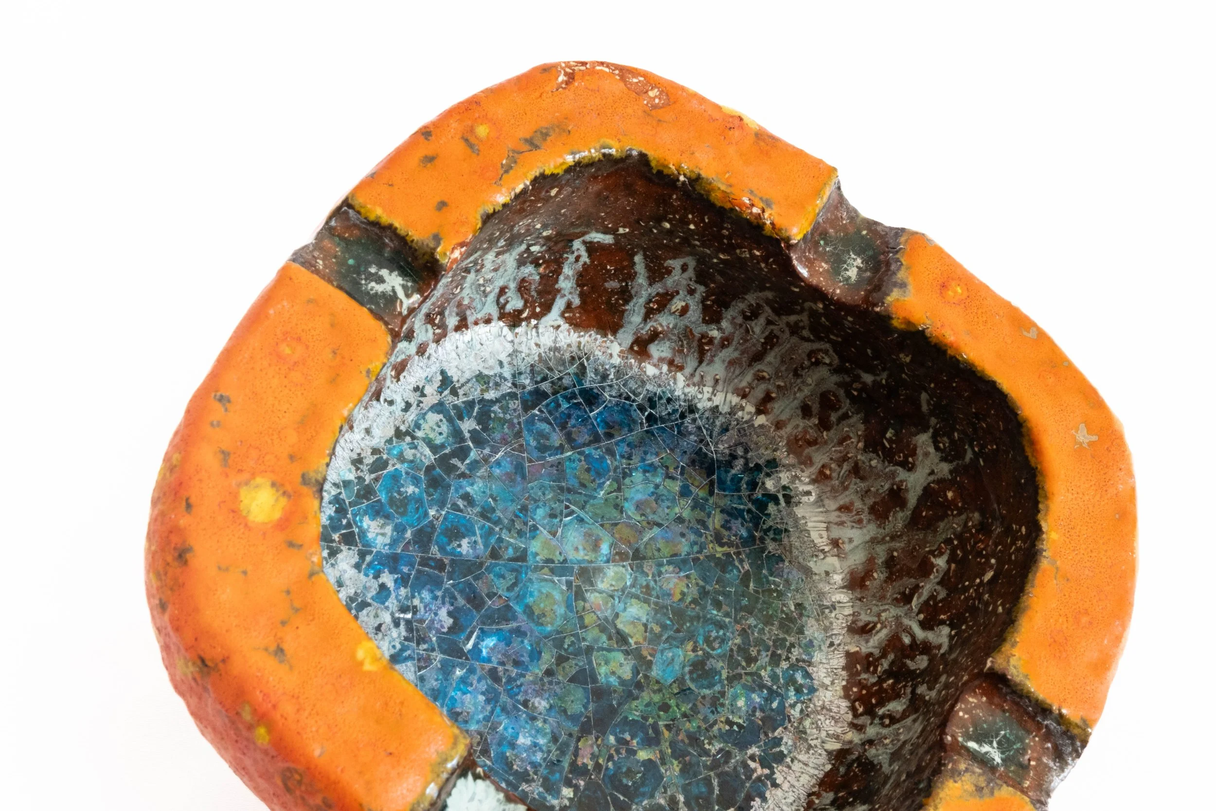 Close-up of a rusty, corroded pipe with orange and black paint, showing a cracked blue inner surface.