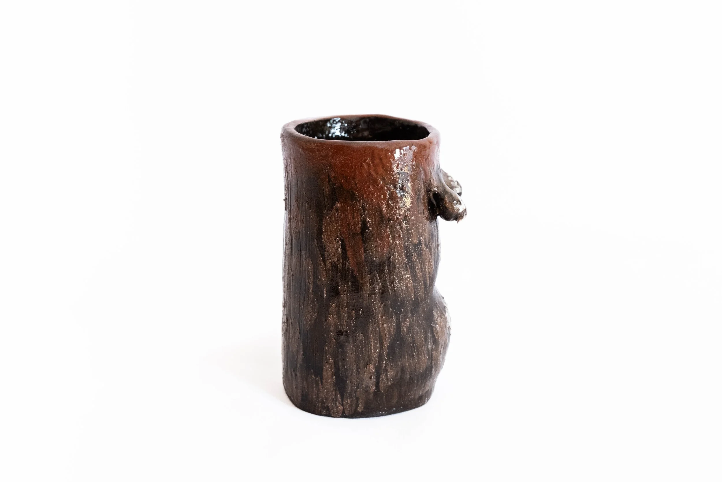 Ceramic vase shaped like a human torso with a facial profile on the side, glazed in dark brown and black tones.