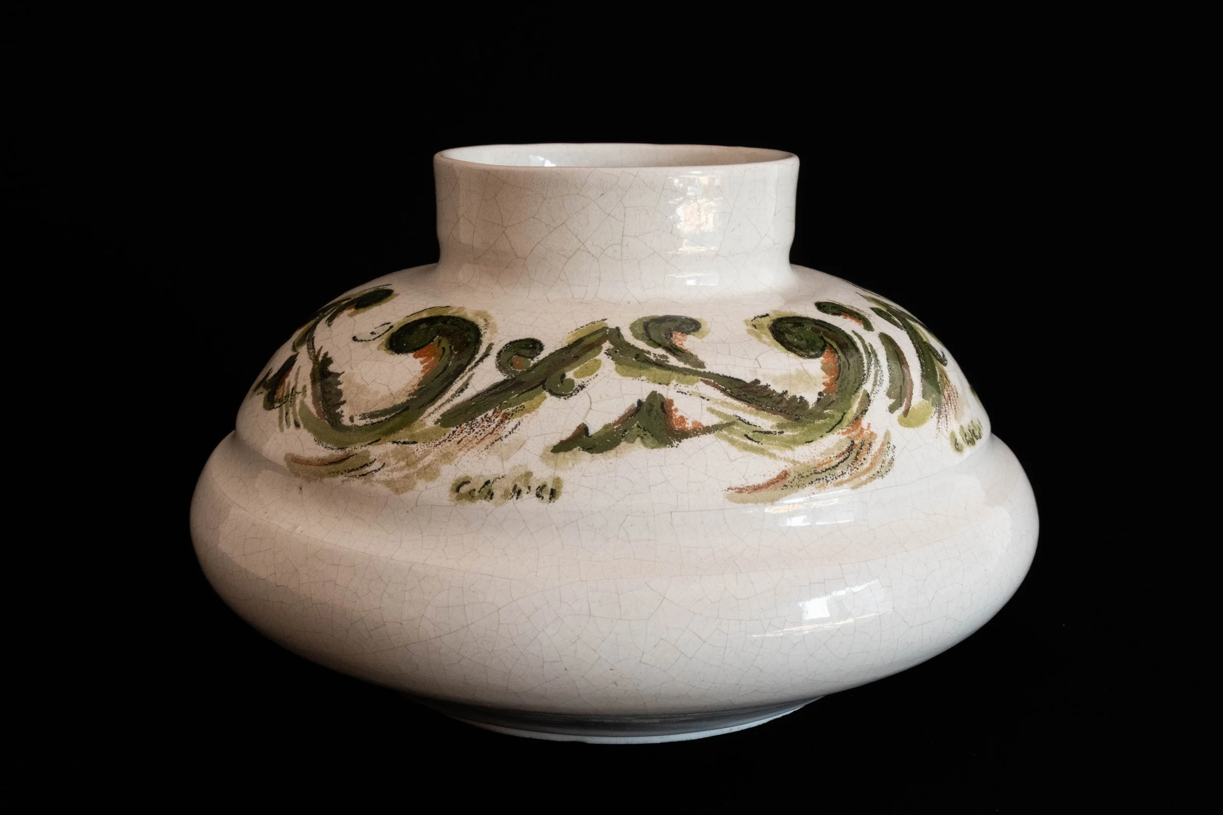Ceramic vase with a rounded body and narrow neck, decorated with abstract green and brown brushstrokes, against a black background.