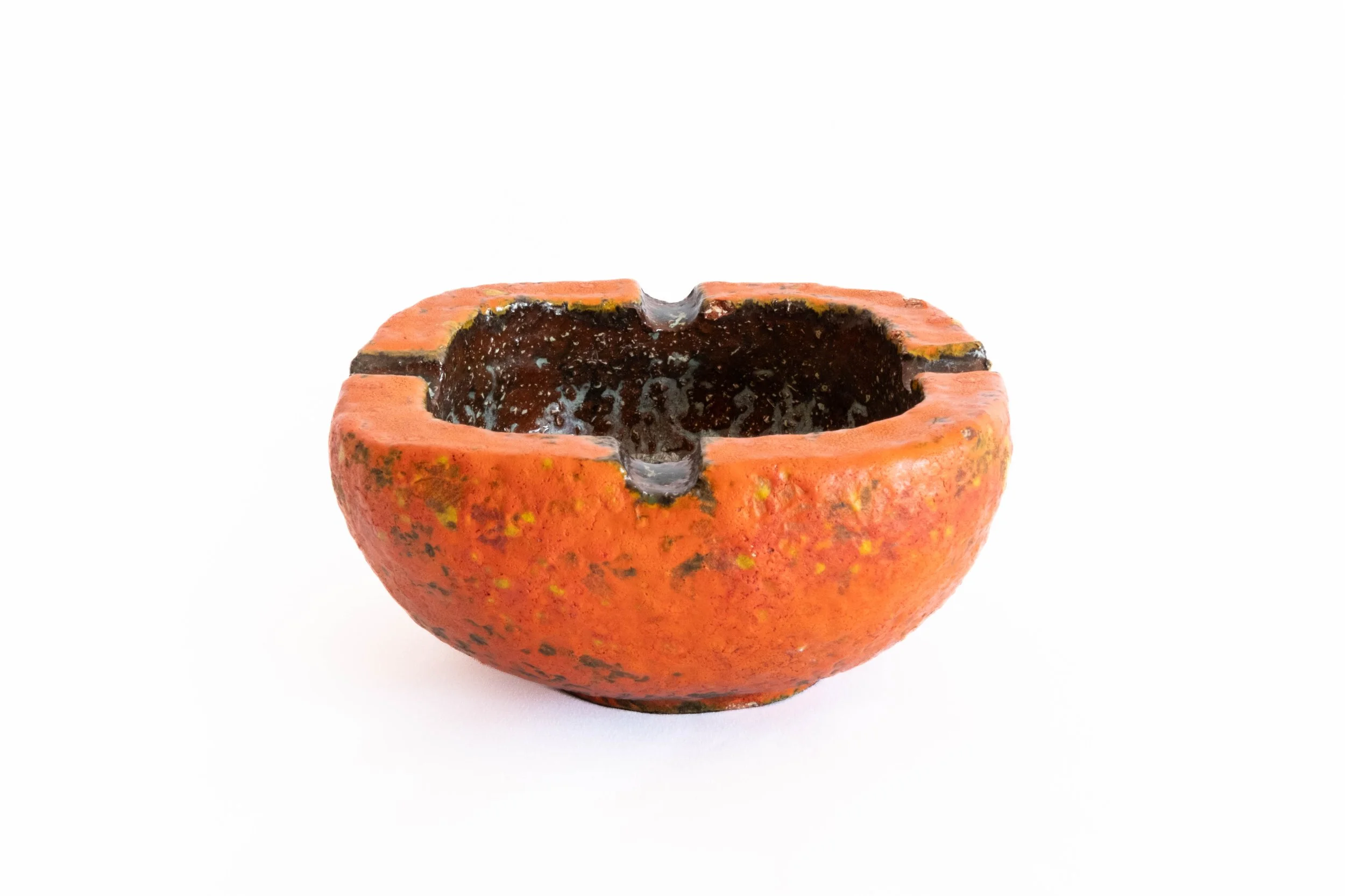 A small, round, orange pottery bowl with a textured surface, blackened interior, and irregular edges, placed against a plain white background.